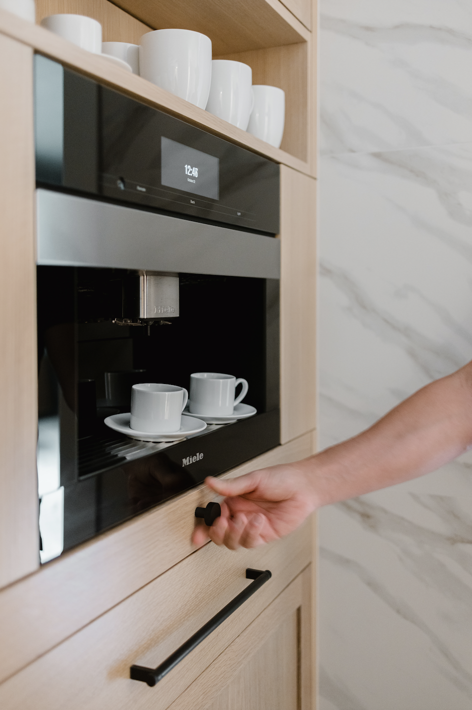Integrated coffee machine in custom cabinets with cups and open shelving above