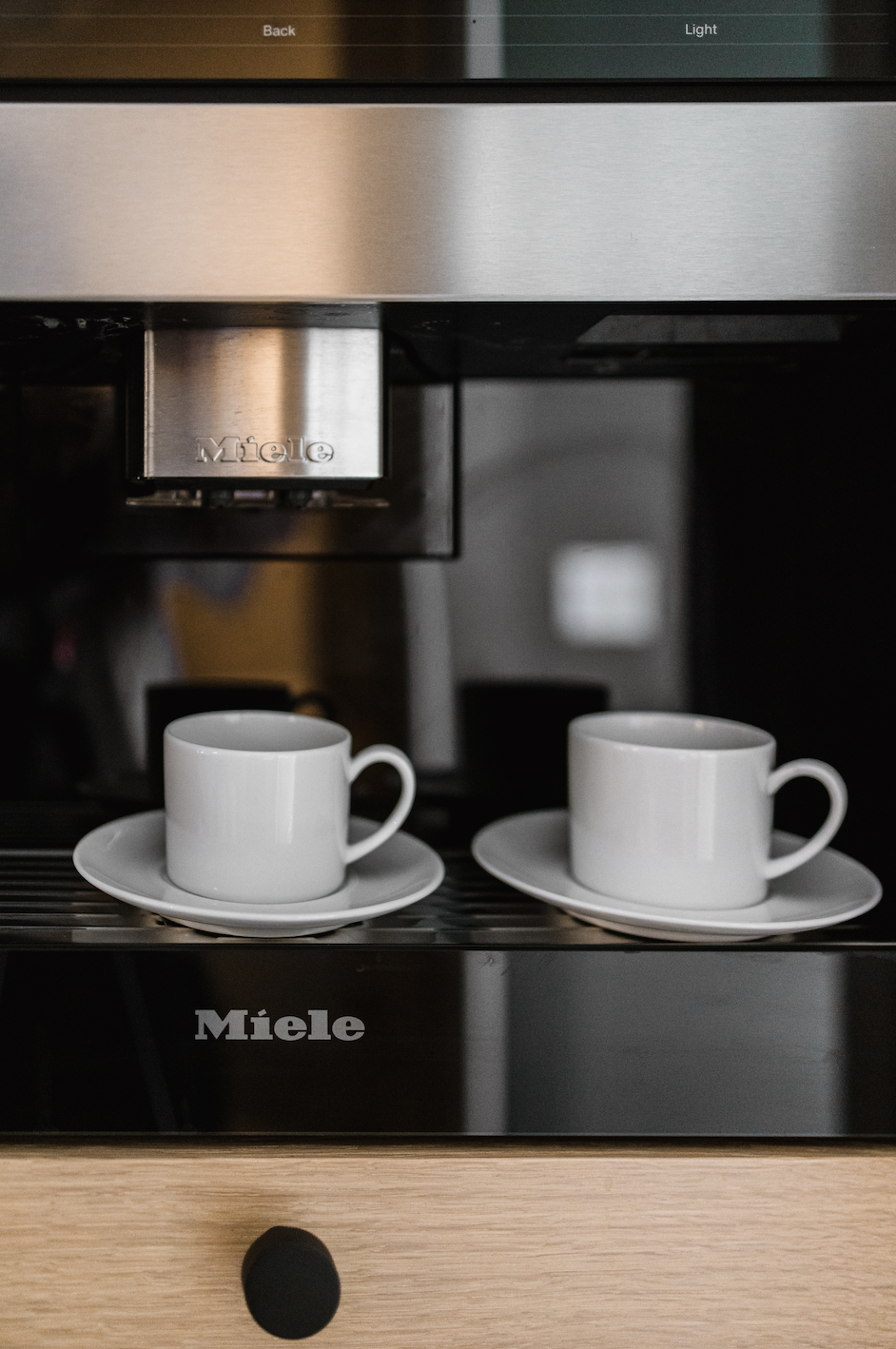 Coffee machine set into modern cabinets with two cups on saucers