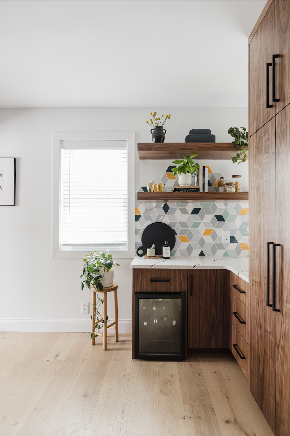 Custom walnut kitchen cabinets with wine fridge, floating shelves, and geometric tile backsplash