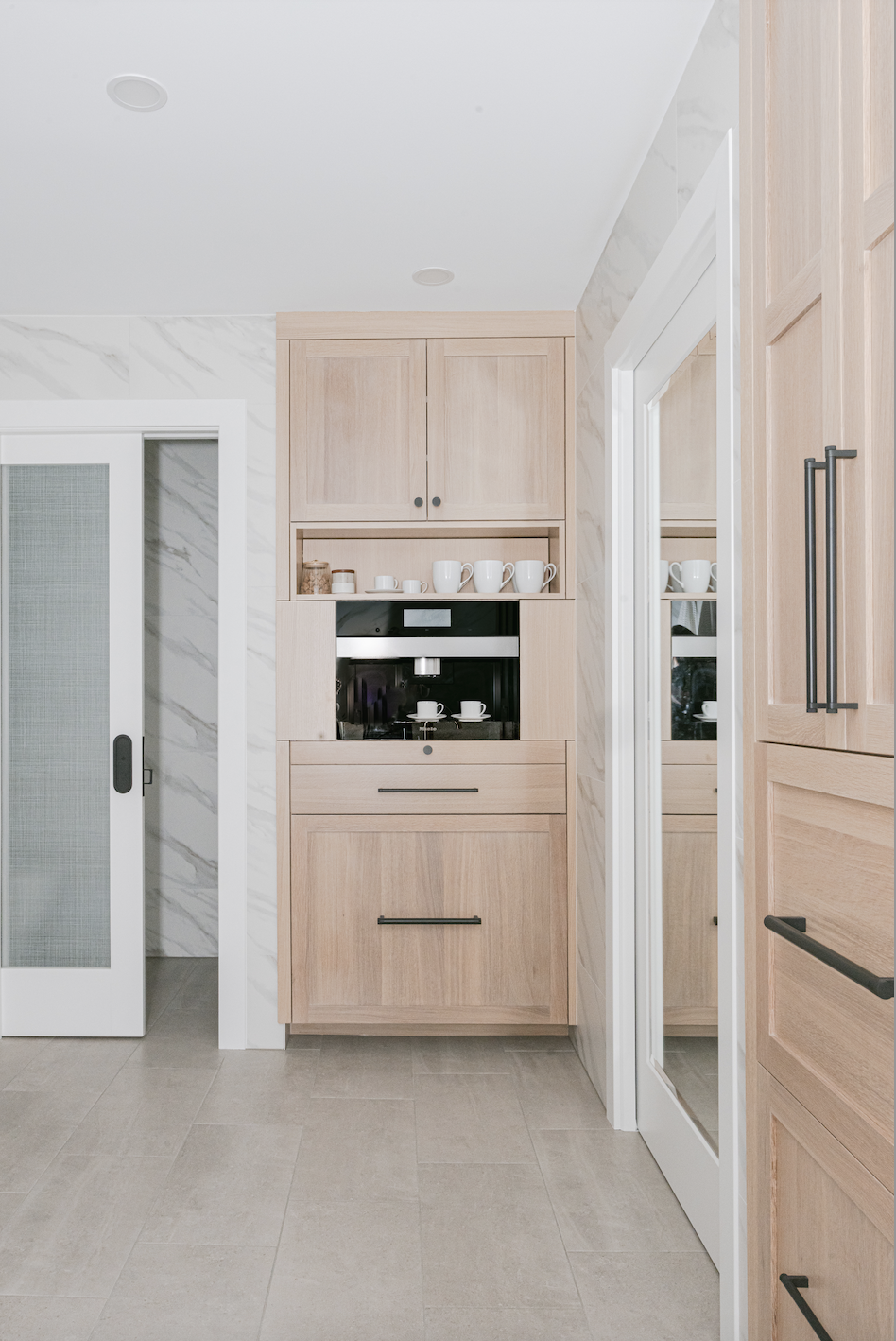 Light wood cabinets with built-in coffee station and open shelving in a bright, modern kitchen nook