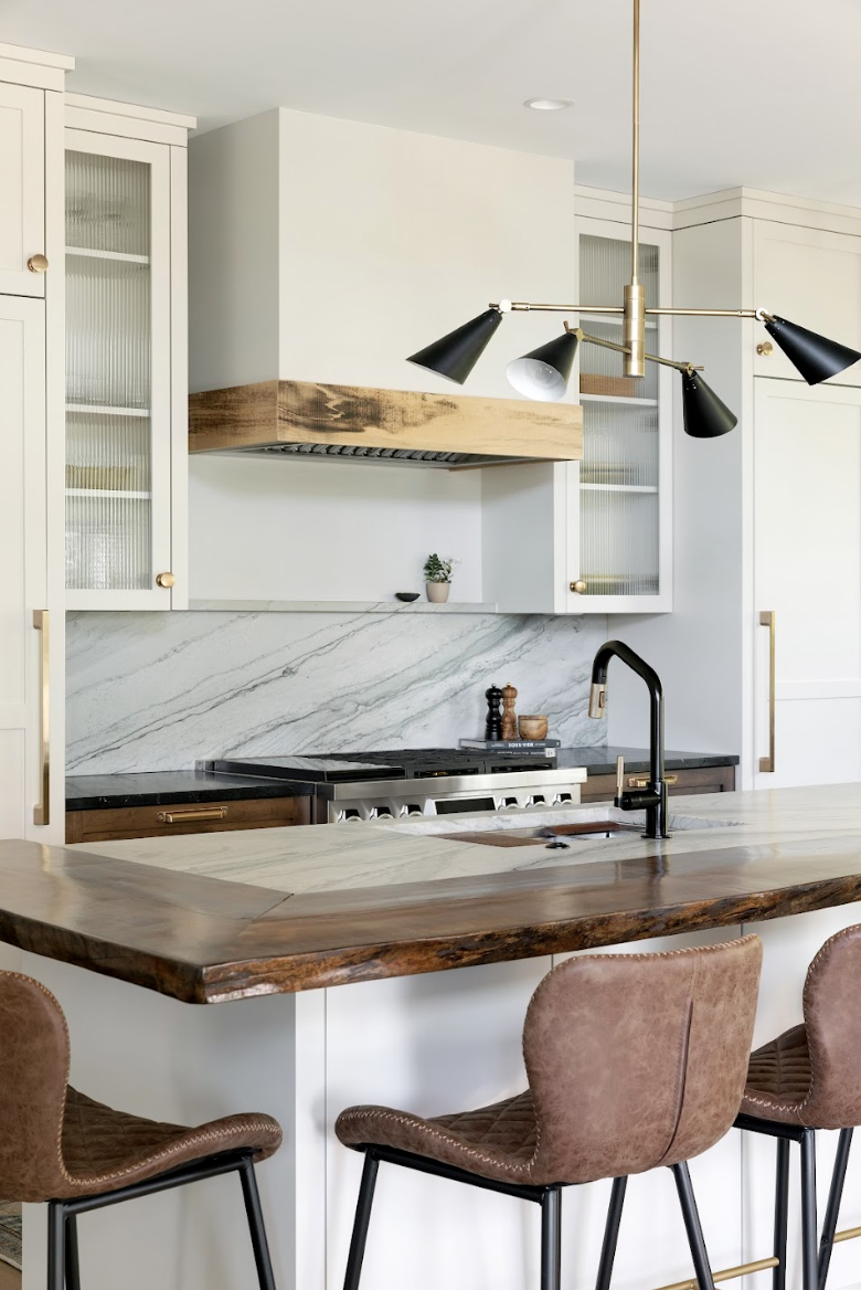 High-end custom kitchen cabinets with mixed wood finishes, glass-front storage, and designer lighting