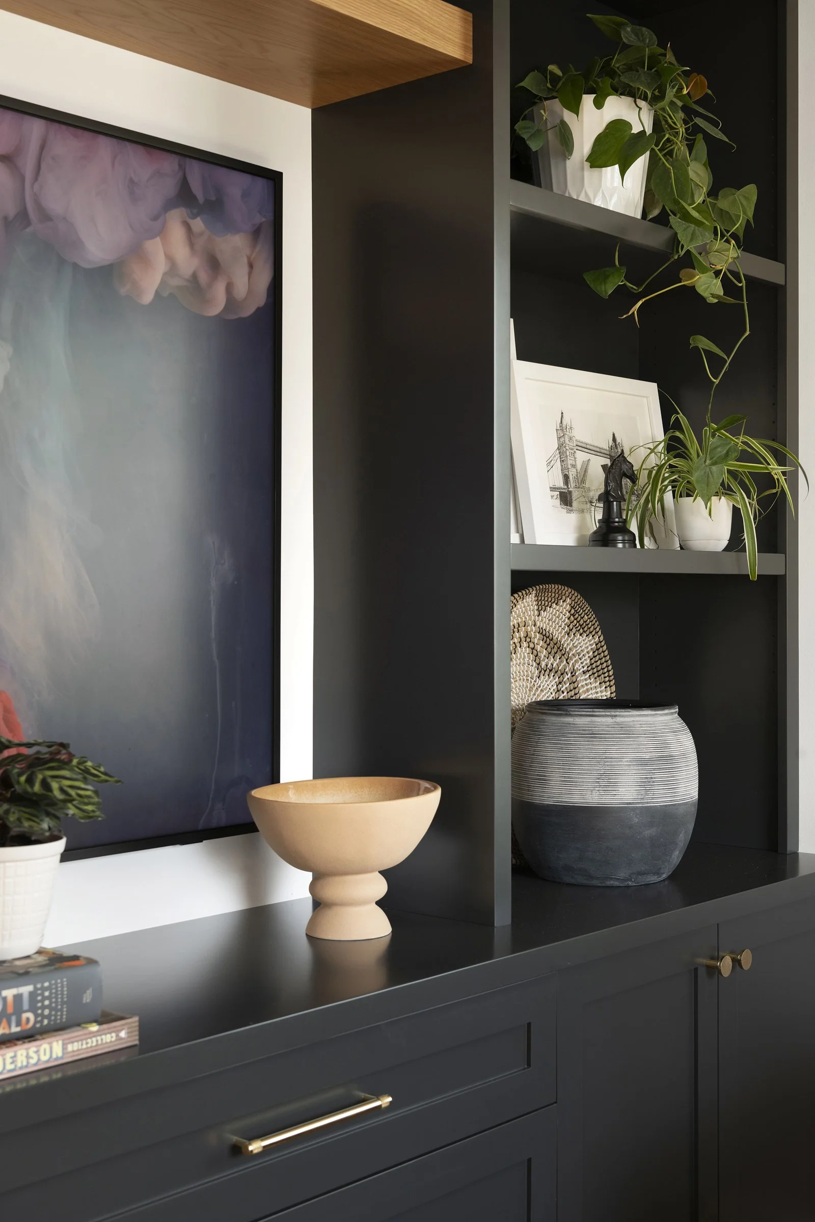 Close-up of custom matte black cabinets with gold hardware and curated open shelving decor