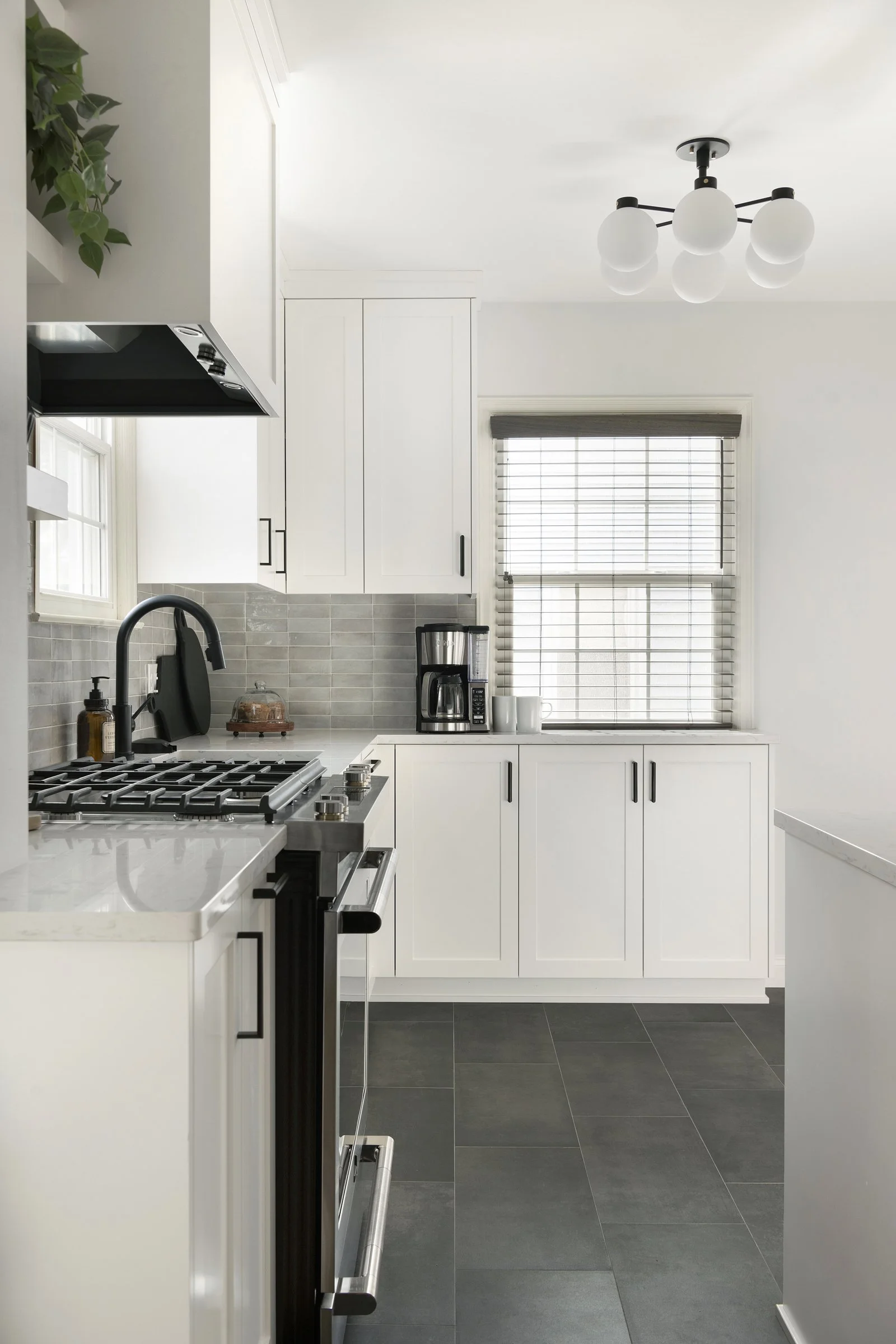 Galley kitchen with white cabinets, black fixtures, and gray tile backsplash.