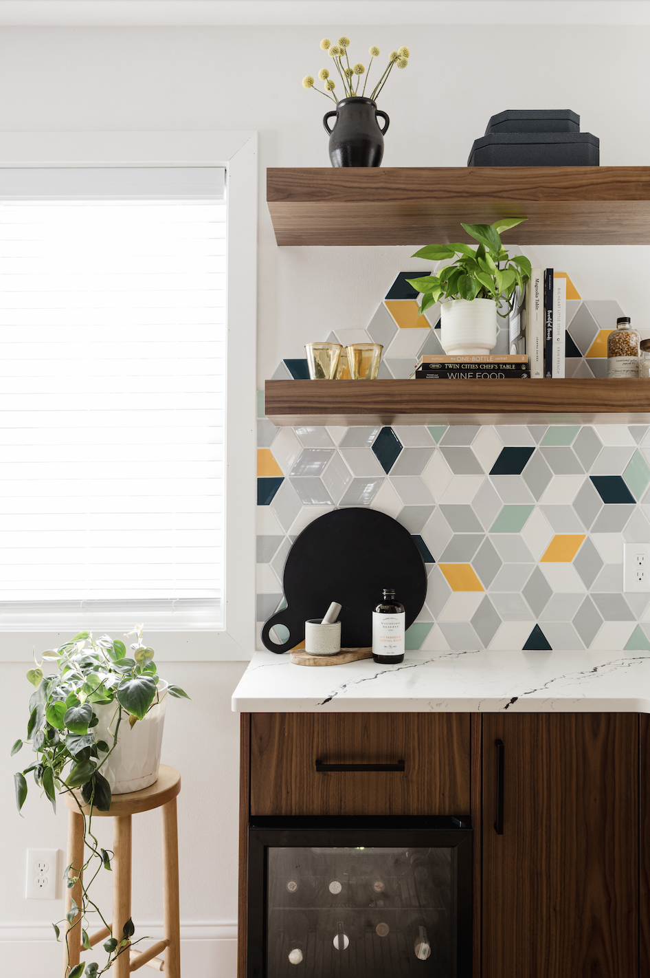Custom walnut kitchen cabinets with colorful geometric tile backsplash and floating wood shelves