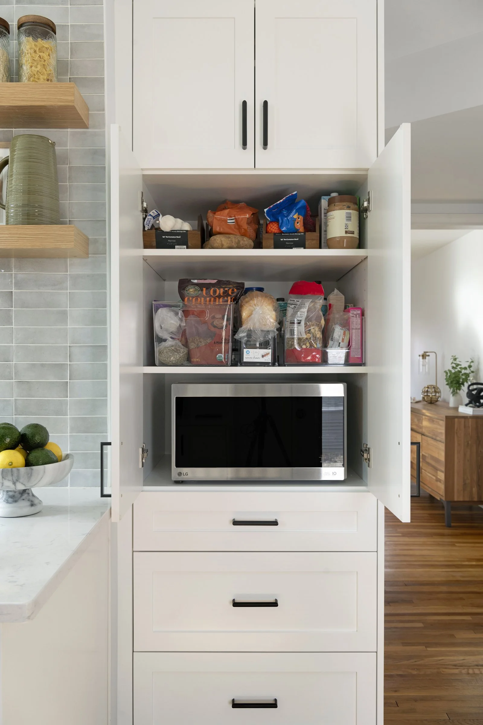 Open pantry cabinets with a built-in microwave and organized storage shelves.