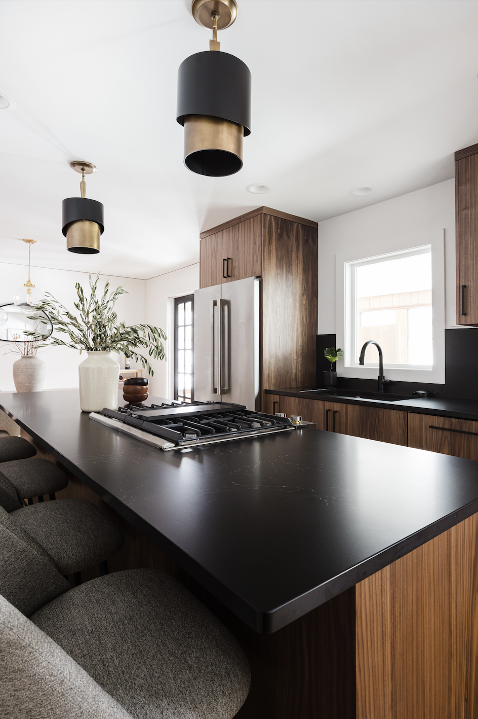 Contemporary kitchen featuring custom walnut cabinets, black island countertop, and brass pendant lights