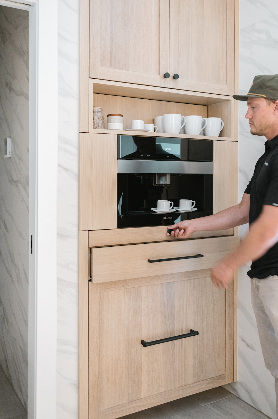 Light wood cabinets with built-in coffee station and drawer being opened