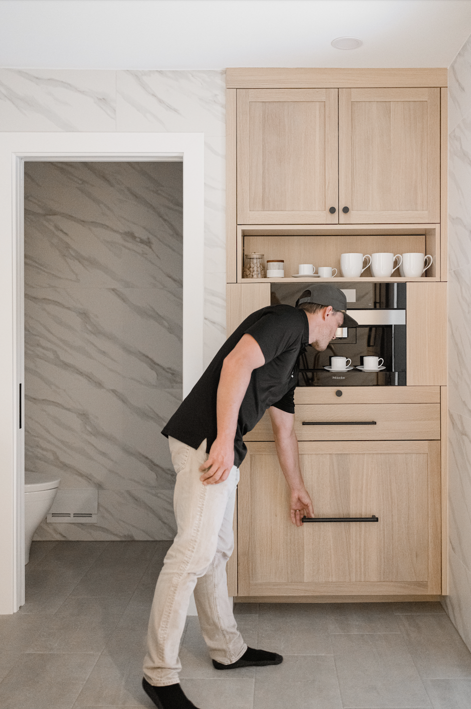 Tall light wood cabinets with hidden coffee station and lower cabinet access