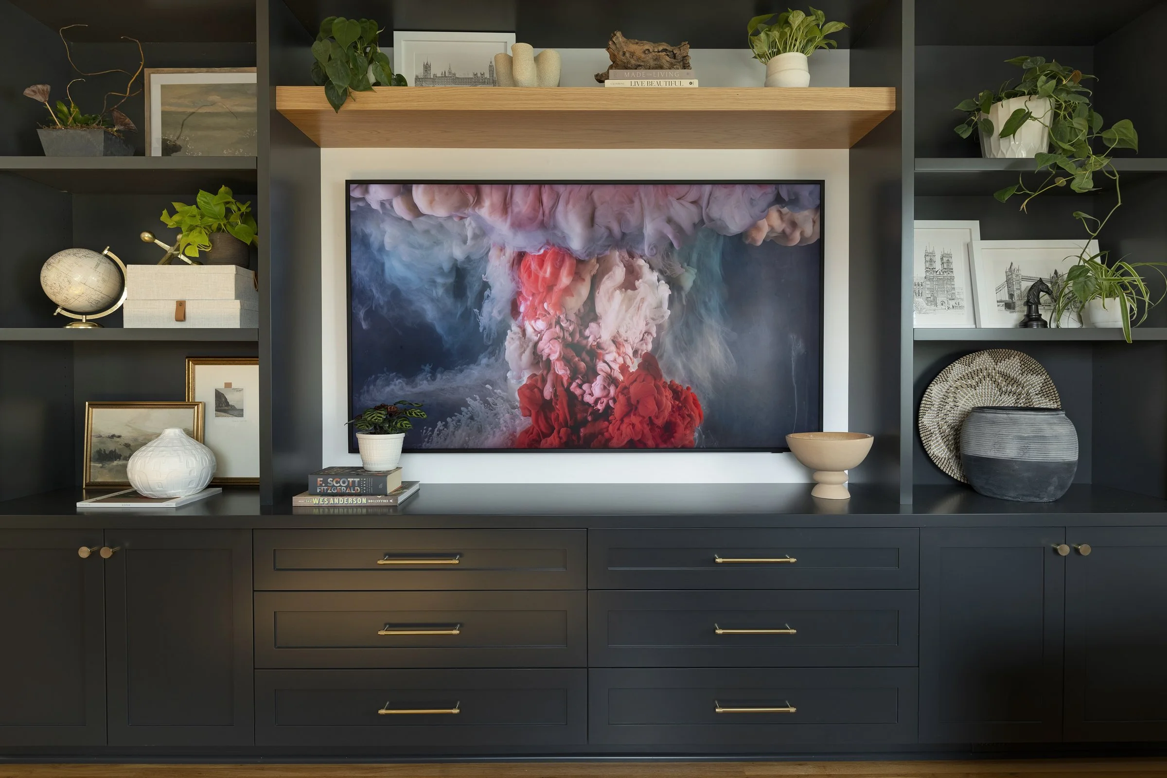 Custom dark cabinets with a floating wood shelf and various decor including plants