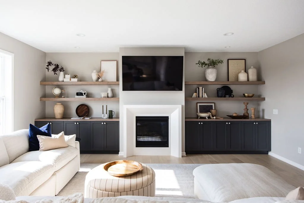 Custom living room cabinetry with black shaker-style built-ins, wood floating shelves, and integrated fireplace surround designed for modern home storage and display.