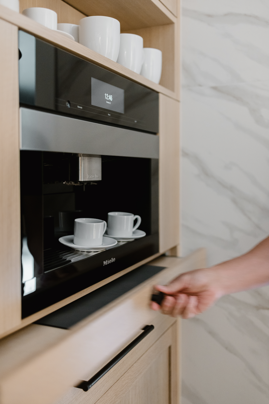 Pull-out drawer beneath built-in coffee machine in modern wood cabinets