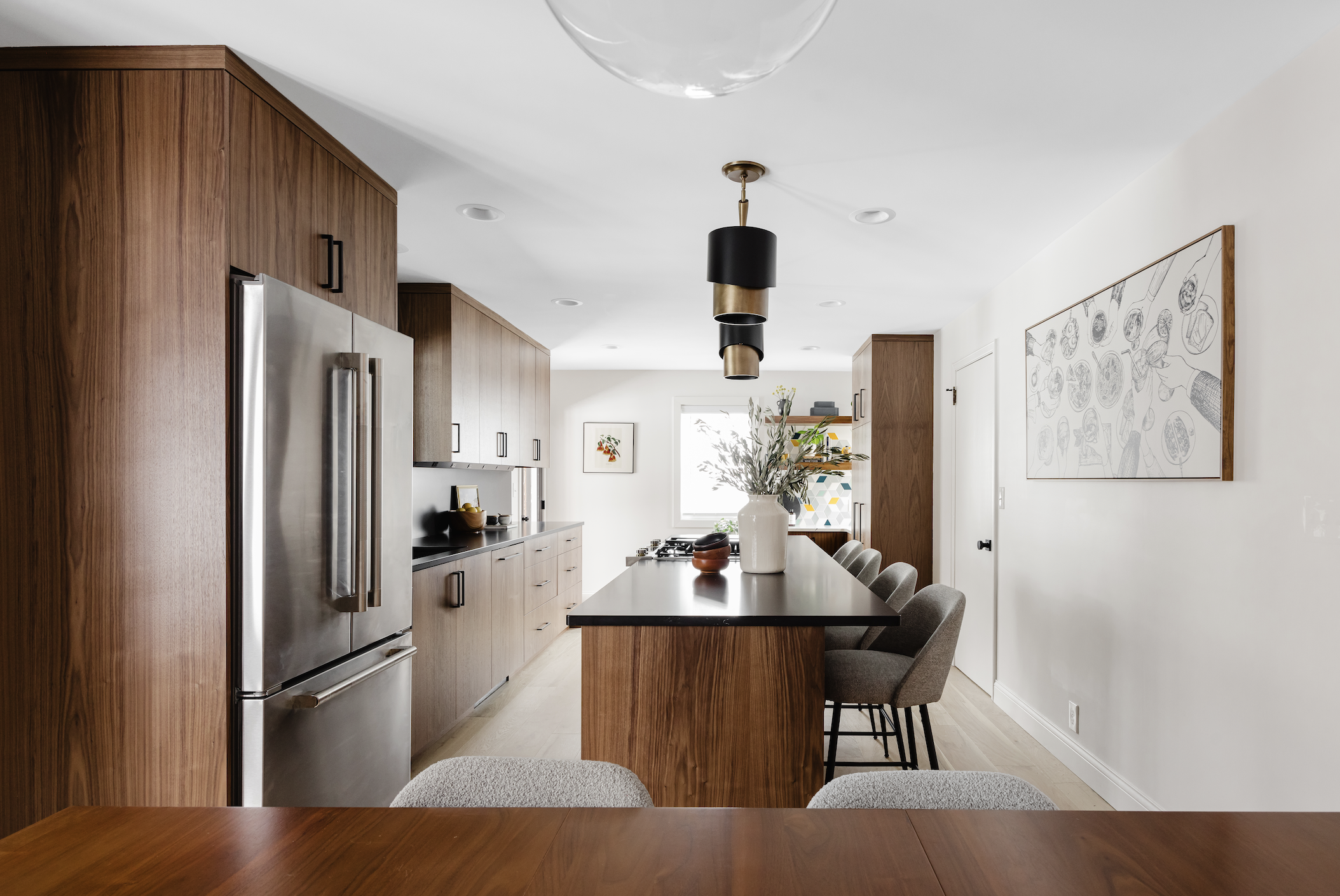 Modern kitchen with custom walnut cabinets, black island countertop, and stainless steel appliances