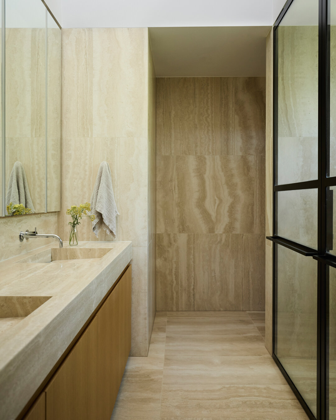 An ode to travertine! Here the master ensuite at our Edward project celebrates cream-toned limestone en masse, paired with timber joinery that echoes the walk-in robe leading to this private bathroom.

Design &amp; Construction by @modify_homes
Photo