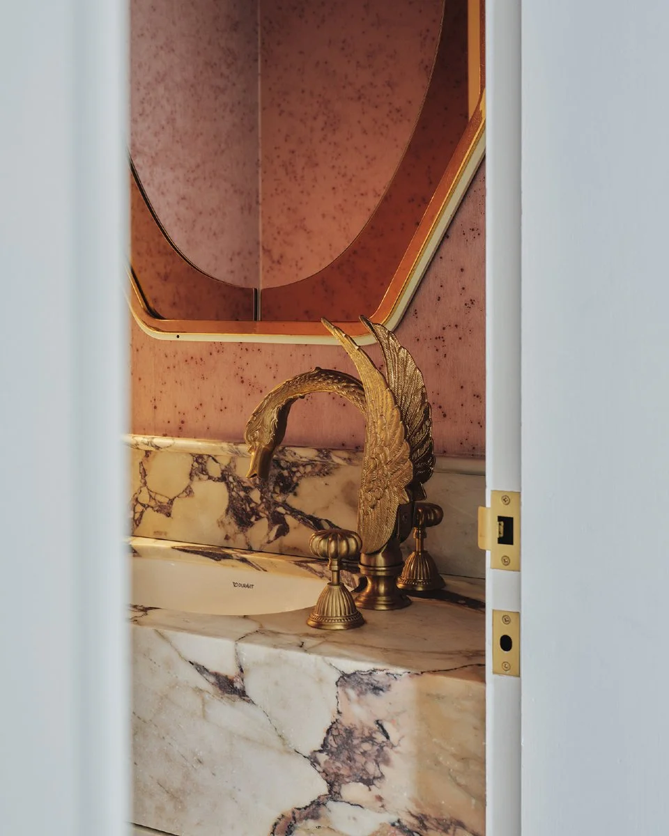 Cascade House | Powder Room 🦢

The powder room is a small but striking space.

A dramatic stone vanity and textured wallpaper are paired with a gold-leaf painted ceiling, lux wall lights and a gold swan-shaped tap &mdash; a specific request from the