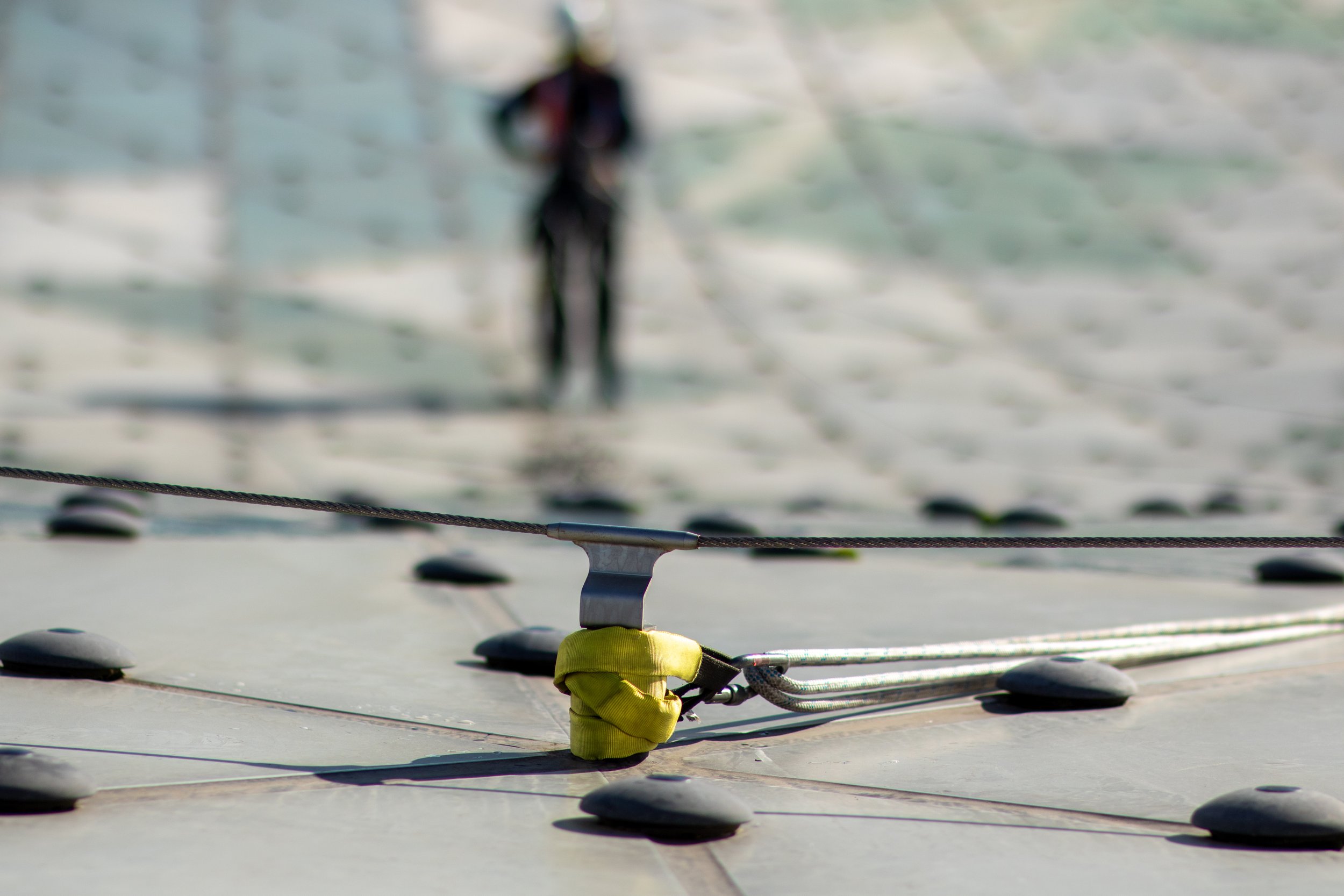 Person climbing the roof of the Sydney Opera House with safety ropes and harnesses.