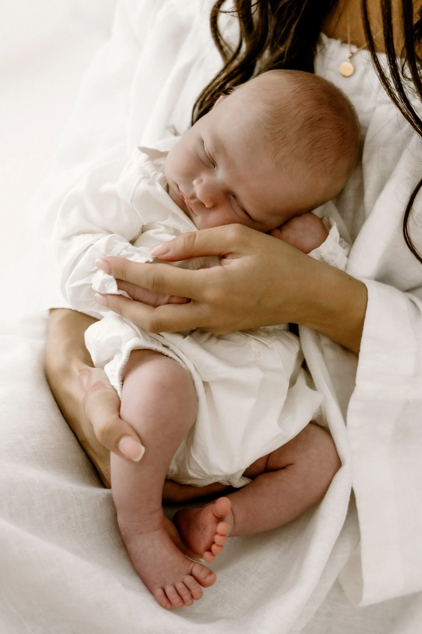 A baby sleeping peacefully while being held in an adult's arms.