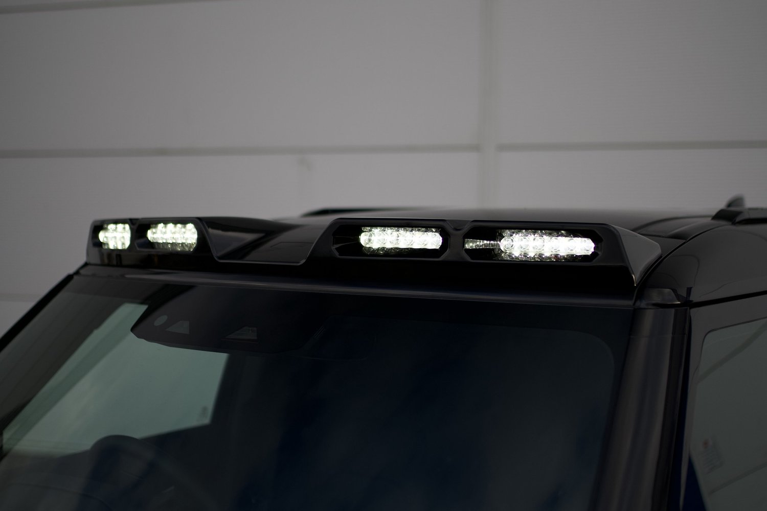 Roof light bar lit across the roof line of a black Land Rover Defender