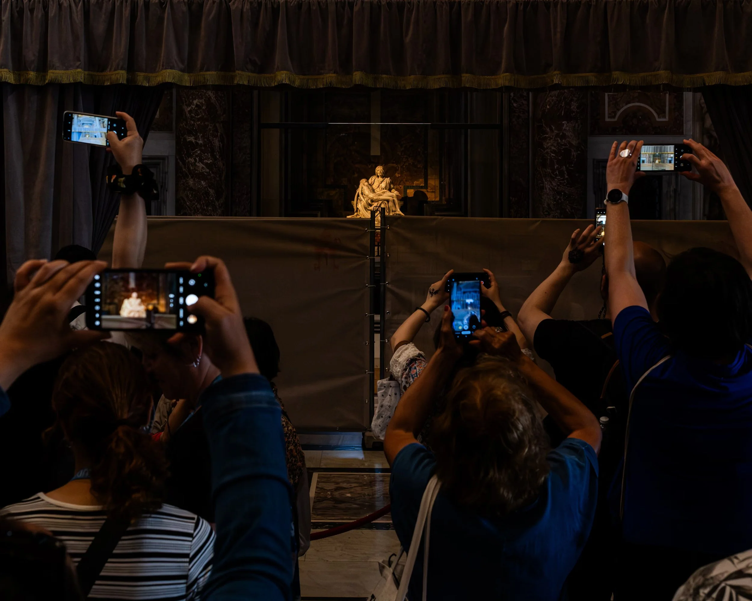visitors raise smartphones towards Michelangelo’s Pietà inside St Peter’s Basilica. 
