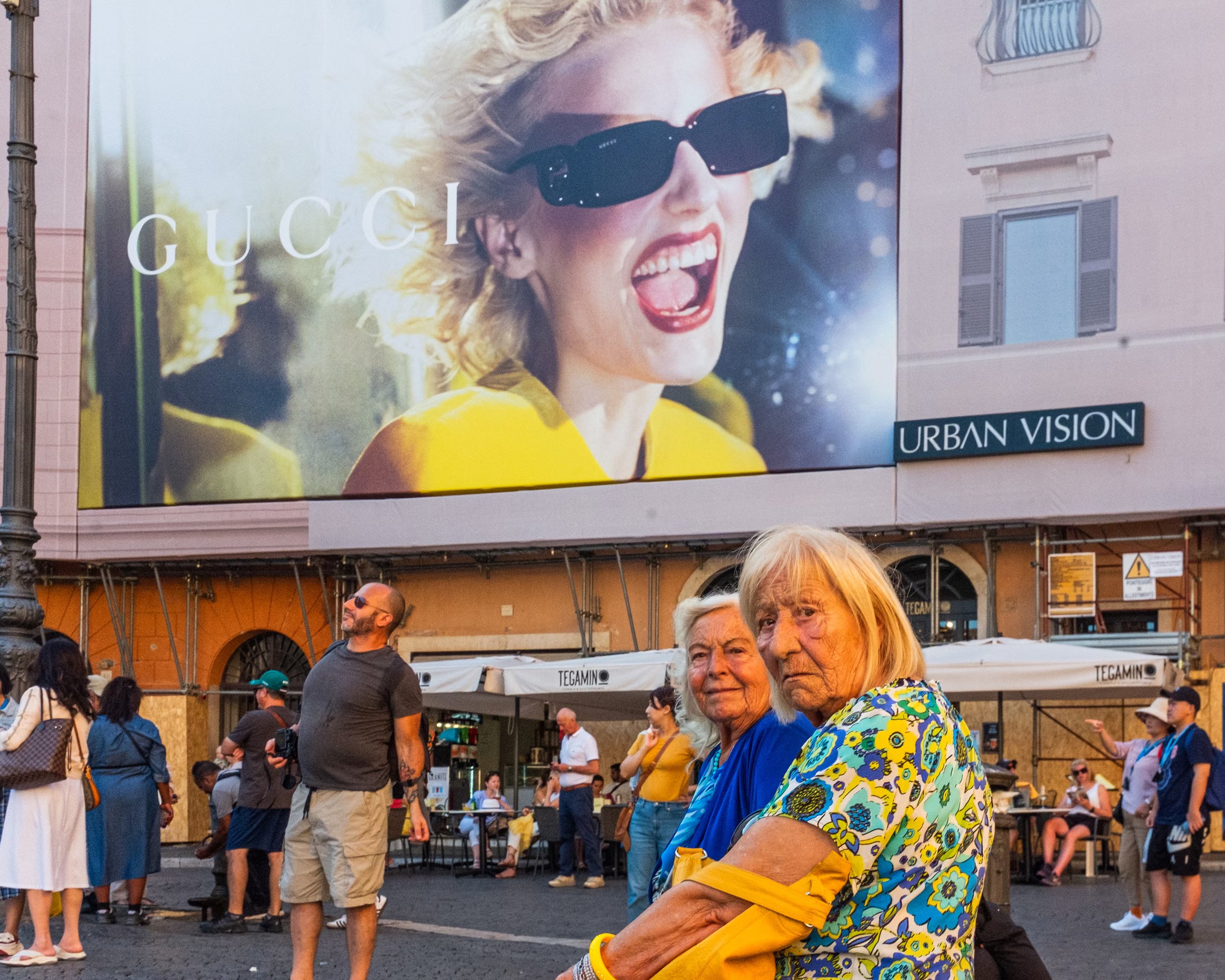 Tourists gather beneath a luxury fashion advertisement in Piazza Navona