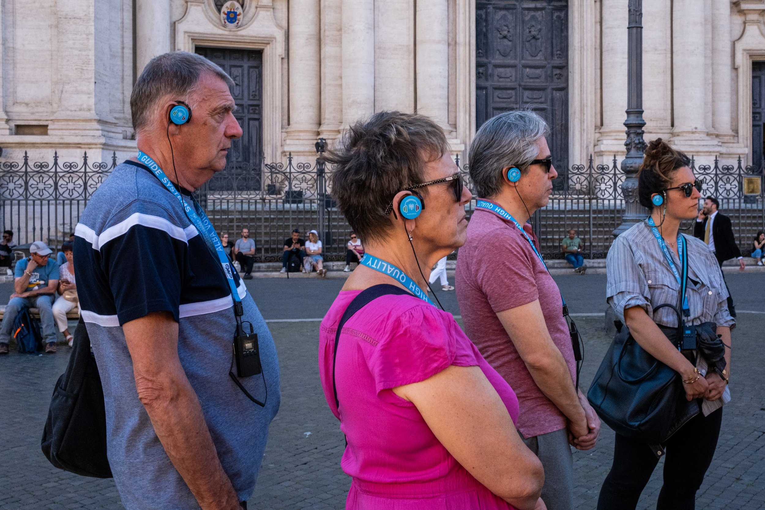 Visitors wearing audio guides cross Piazza Navona.