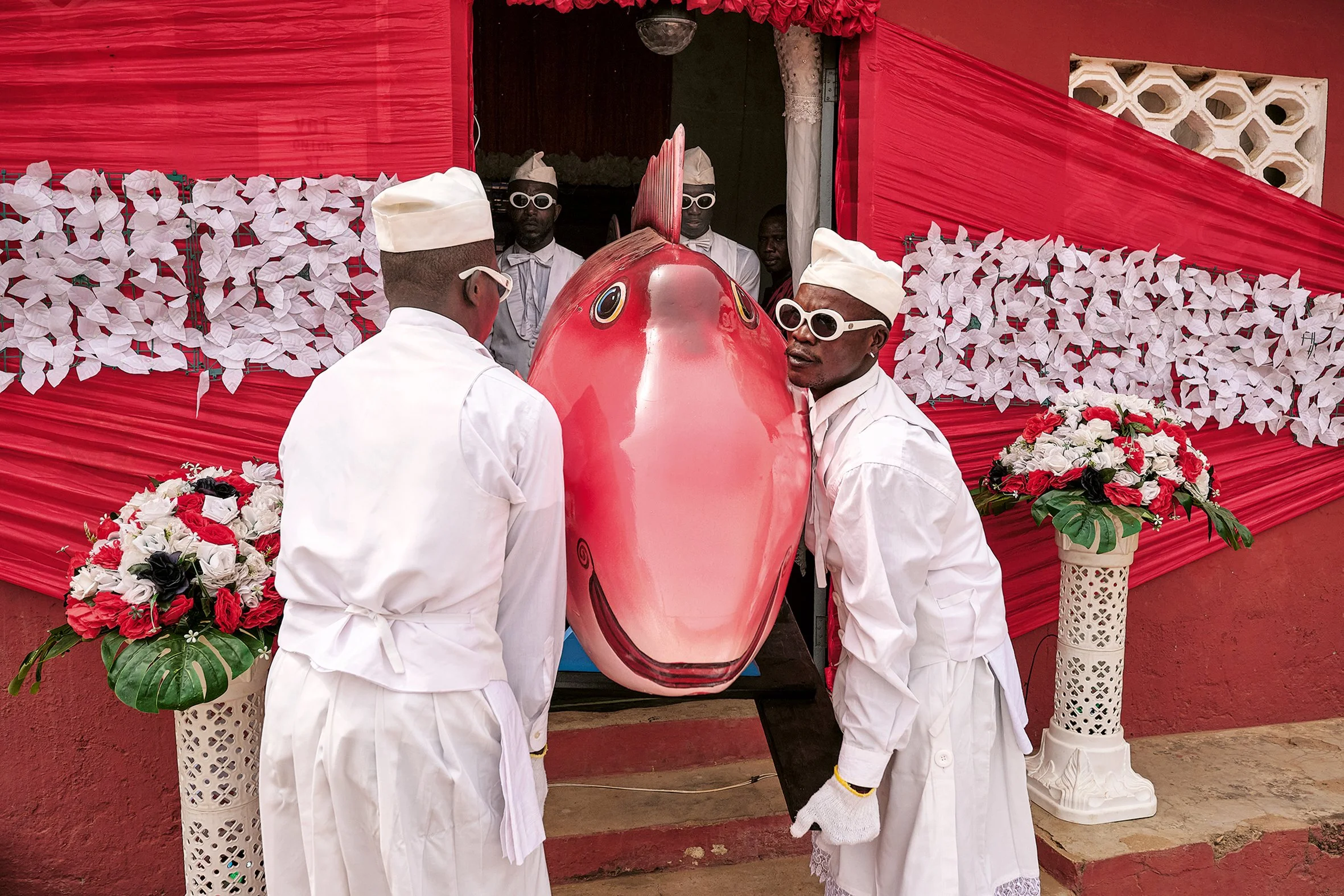 The eldest member of the family, a fishmonger, is honoured by her relatives with a fish coffin. Nana Otafritsa takes care of the laying out and decoration of her room the evening before. On Saturday, he and his Coffin Dancers dance with
the coffin to