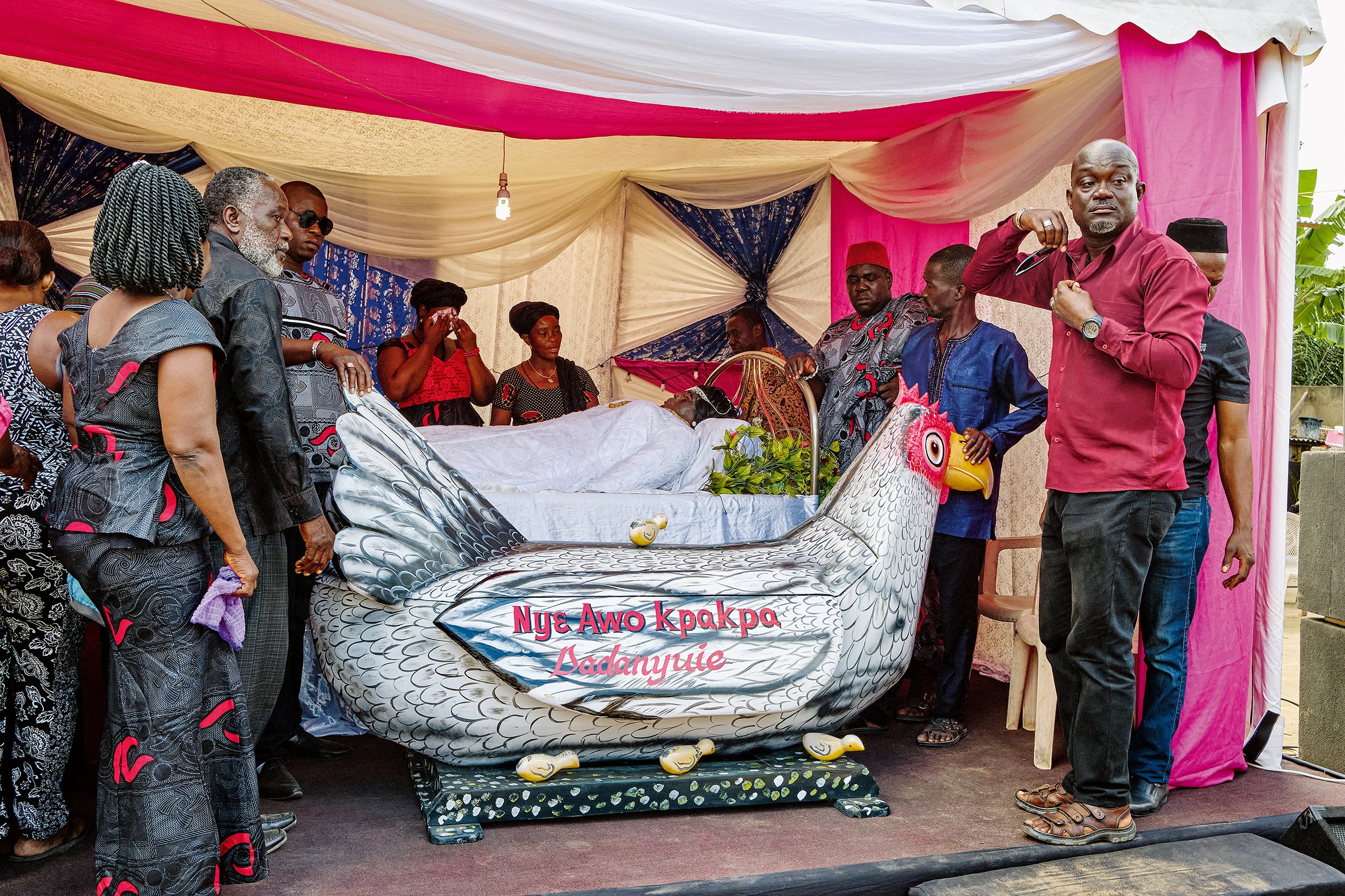 Relatives at the funeral service of their mother and grandmother, who is laid out in a tent next to her coffin.– Central Region, 2018. (Undertaker unknown; coffin: Kudjoe Affutu)
© Regula Tschumi