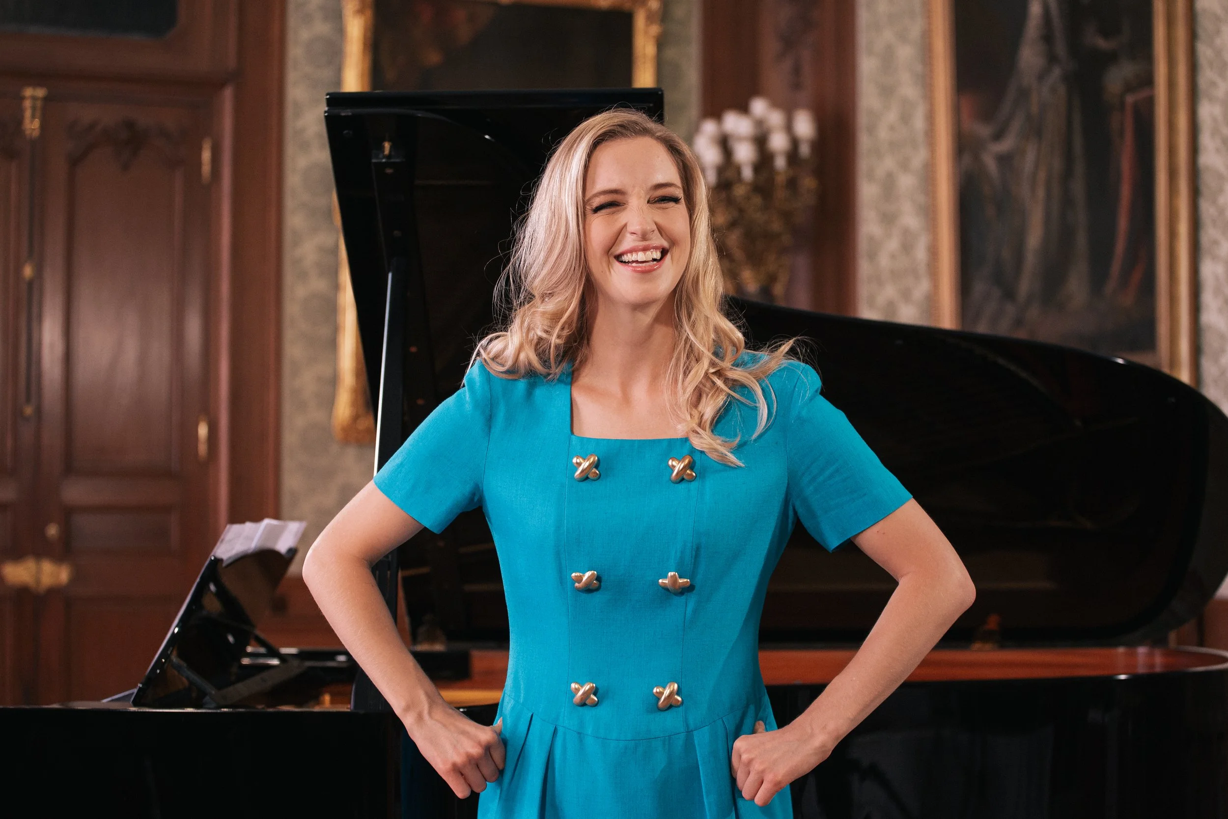 Portrait of Julia Dawson in blue dress smiling in front of piano