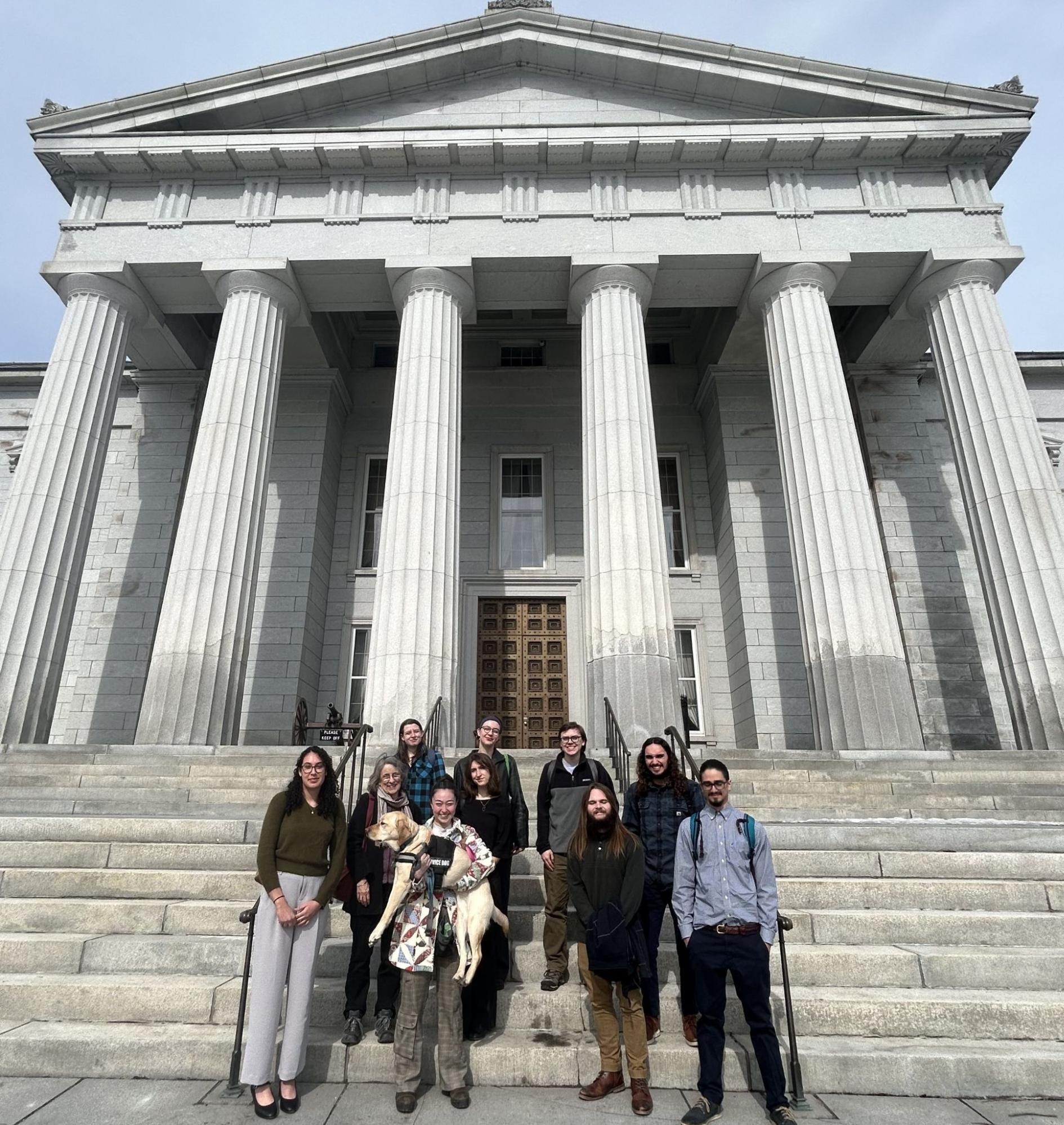 �����ؿ� students stand in front of the Vermont Statehouse on a sunny March day