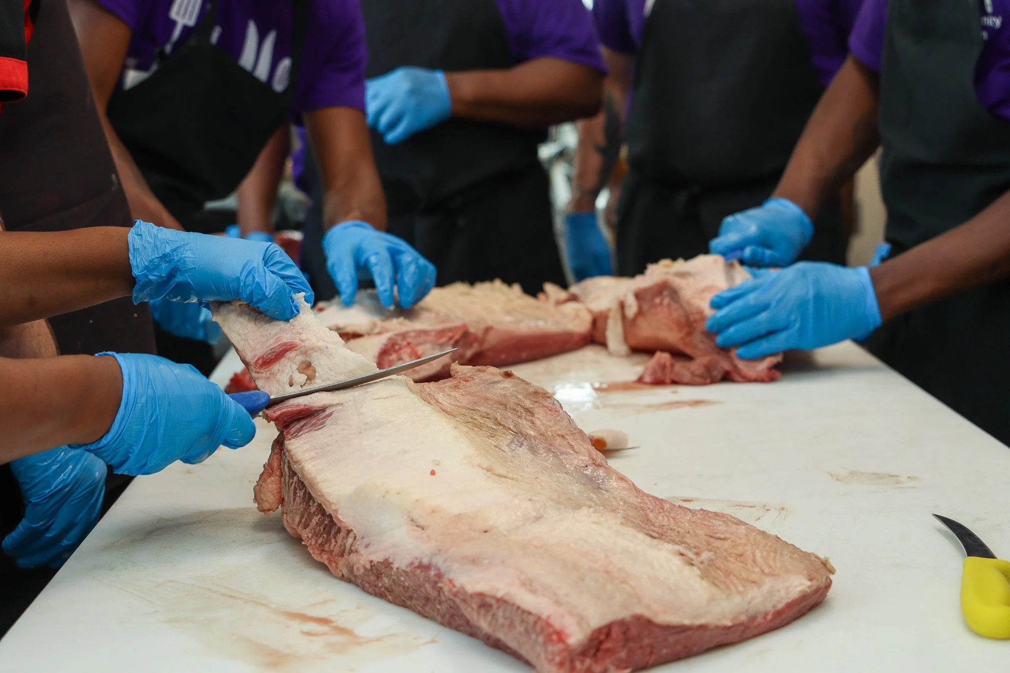 photo of CKP students' hands as they cut brisket
