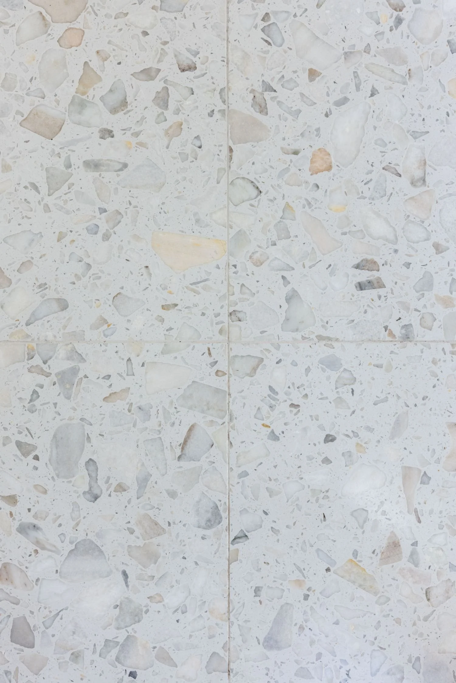Close-up of a terrazzo tile wall with various small, irregularly shaped stones embedded in a white matrix.