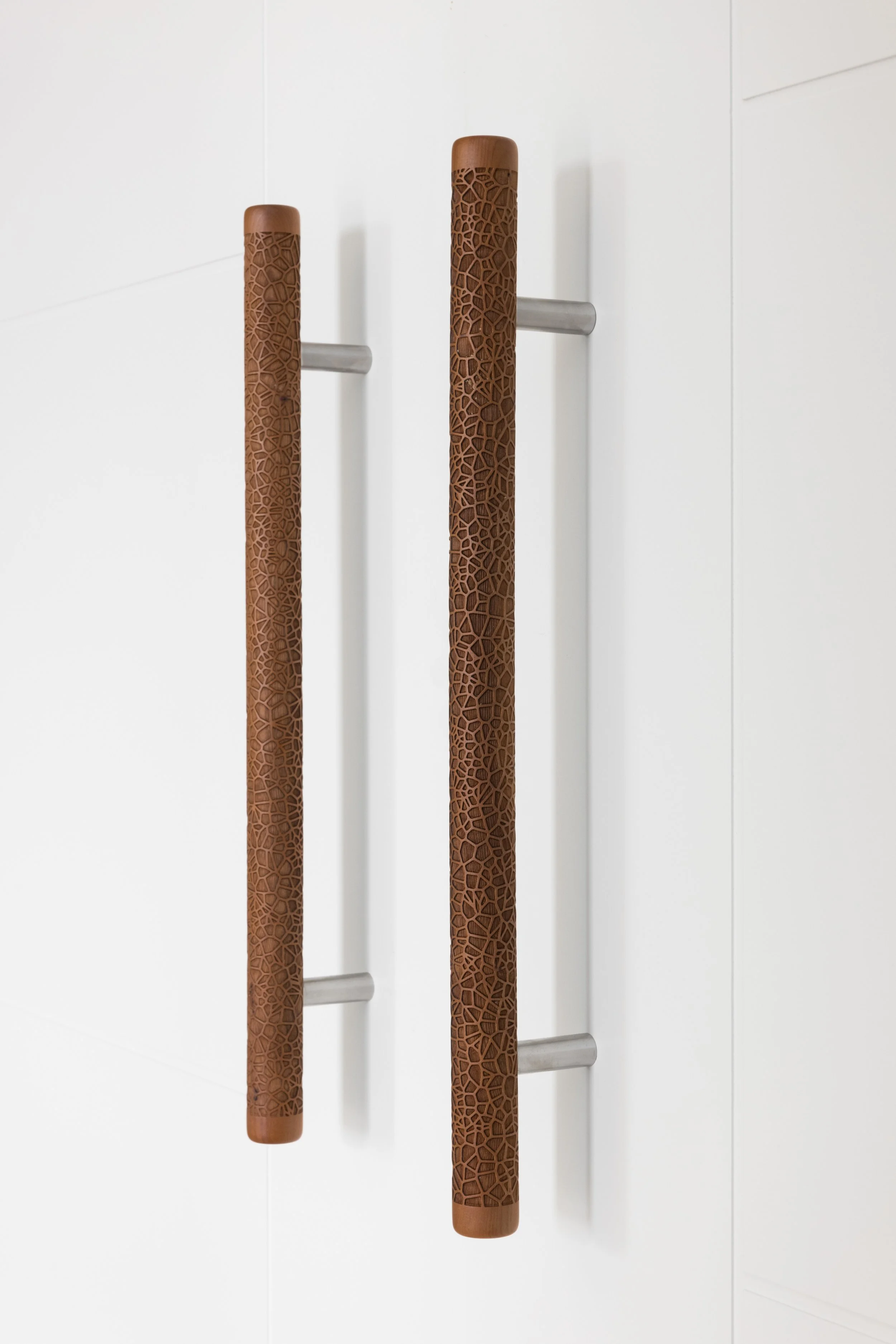 Close-up of two brown textured handrails mounted on a white doors.