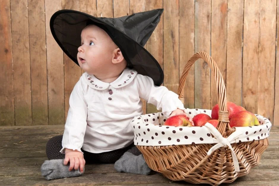 baby in witch hat with basket of apples