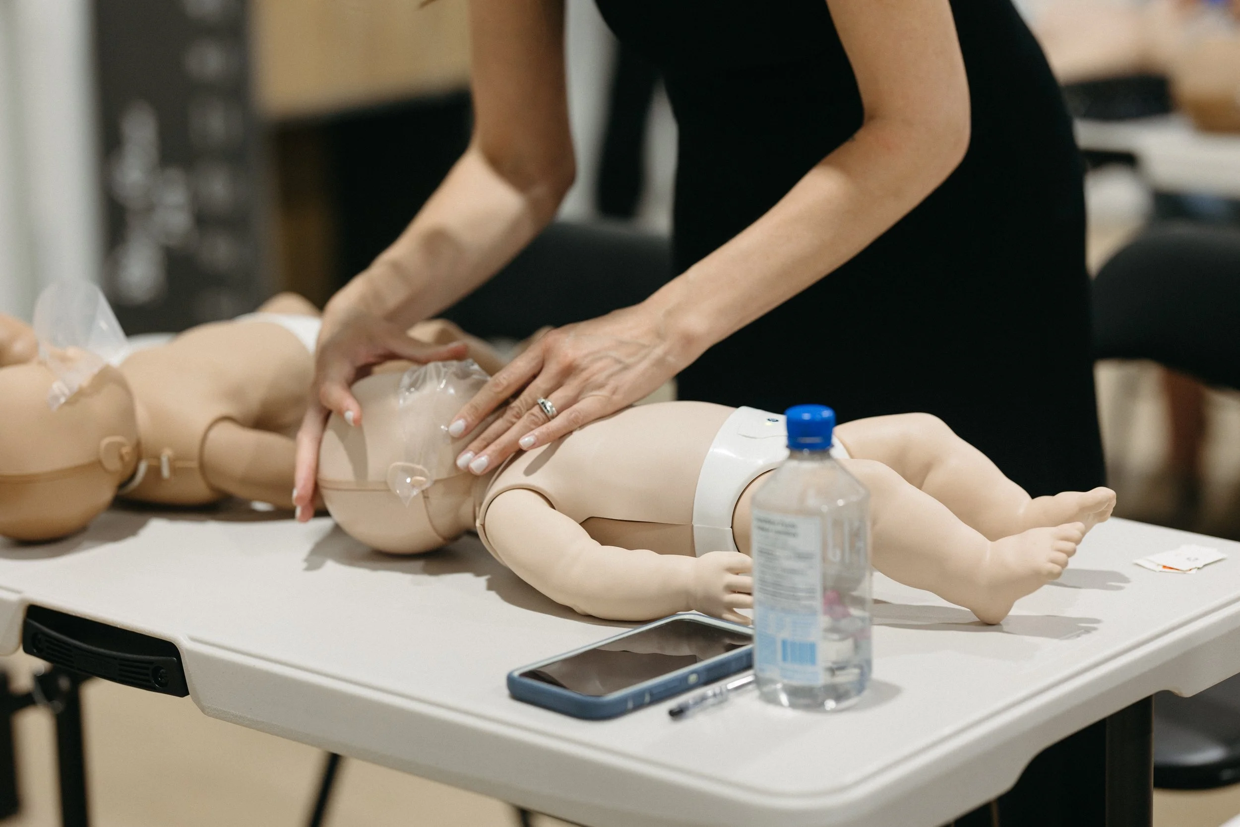 Parent preparing to give rescue breaths on an infant manikin