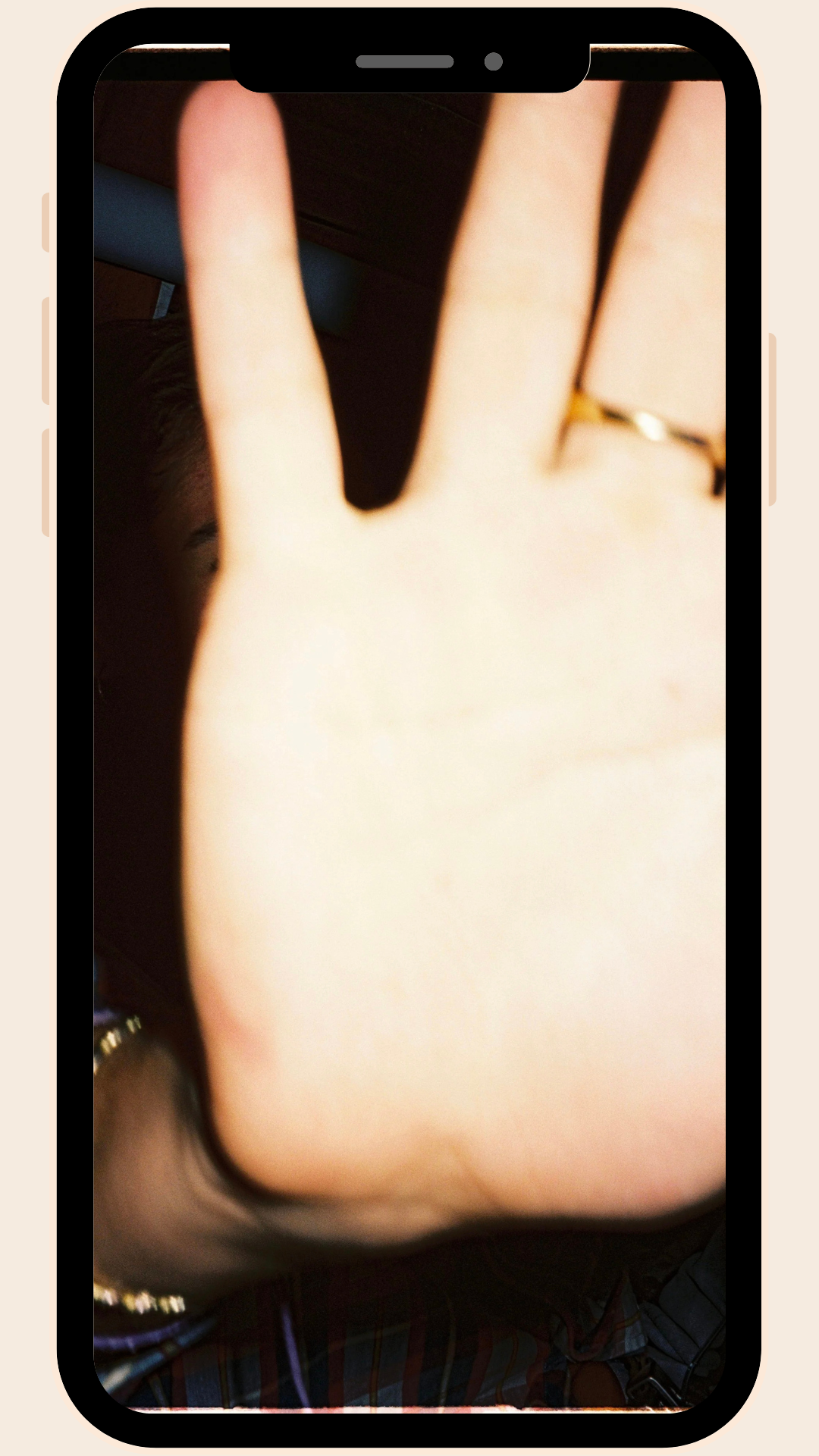 A person holds their hand up toward the camera in a candid, unposed moment. A gold ring catches the light. The image feels intimate and unperformed — captured for no audience.
