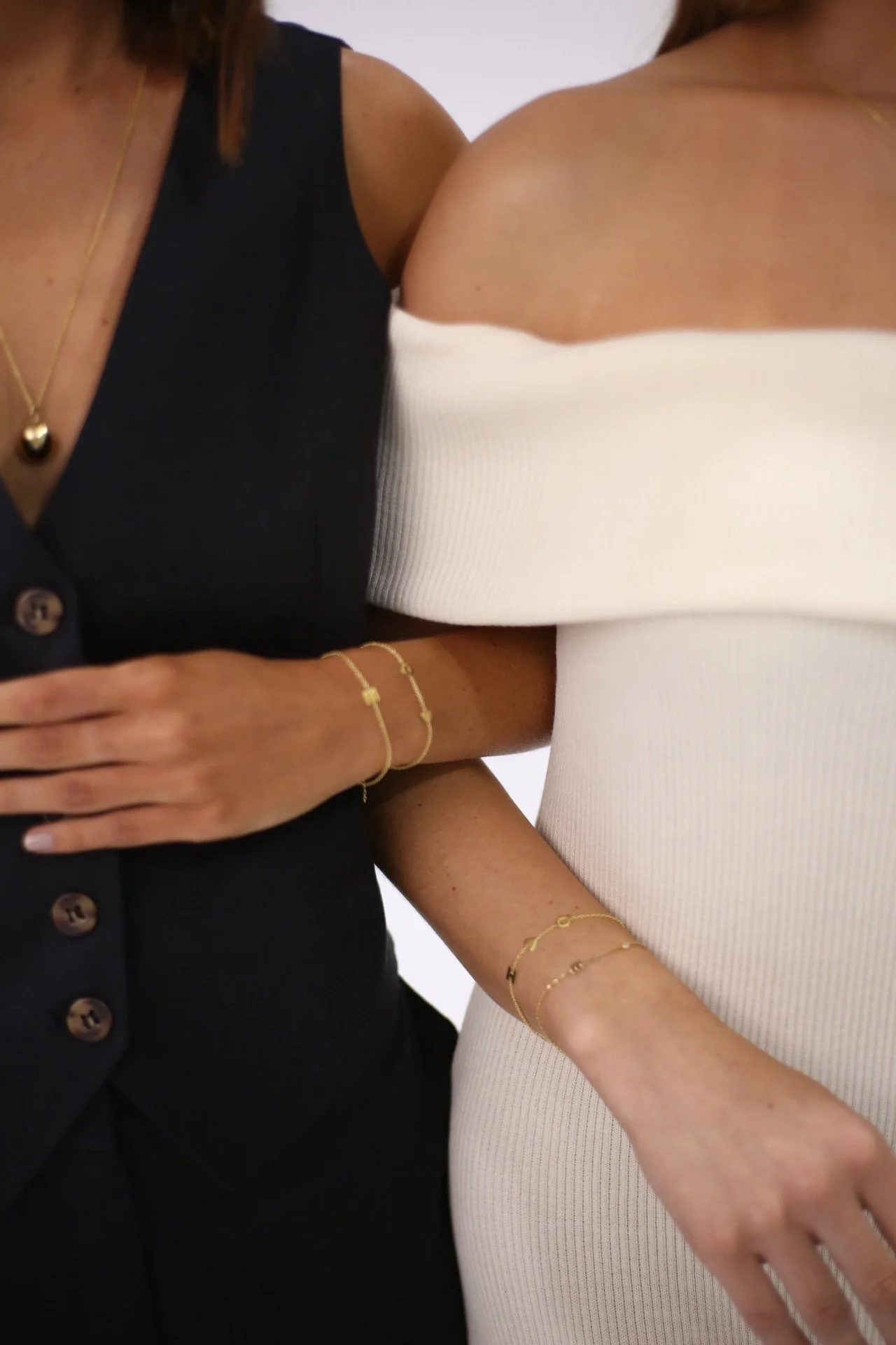 Two women with arms linked wearing delicate layered gold bracelets — fractional communications partnership for women founders and senior leaders, Coast Road Creative