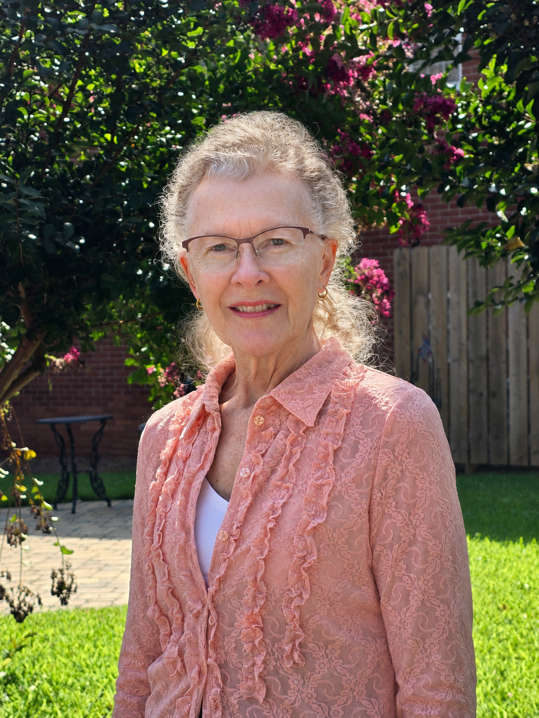 An older woman wearing glasses and a pink sweater.