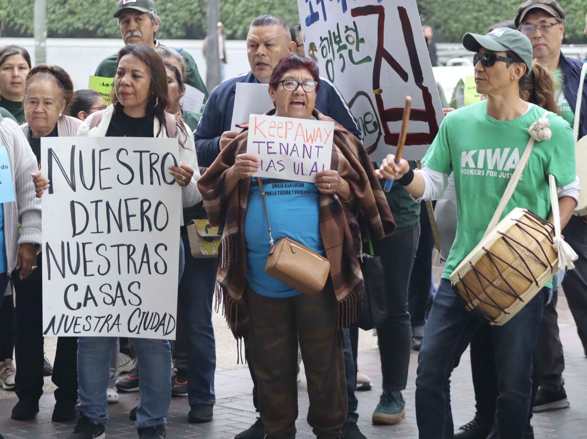 Advocates holding signs: "NUESTRO DINERO NUESTRAS CASAS NUESTRA CIUDAD" AND "KEEP AWAY, TENANT HAS ULA".