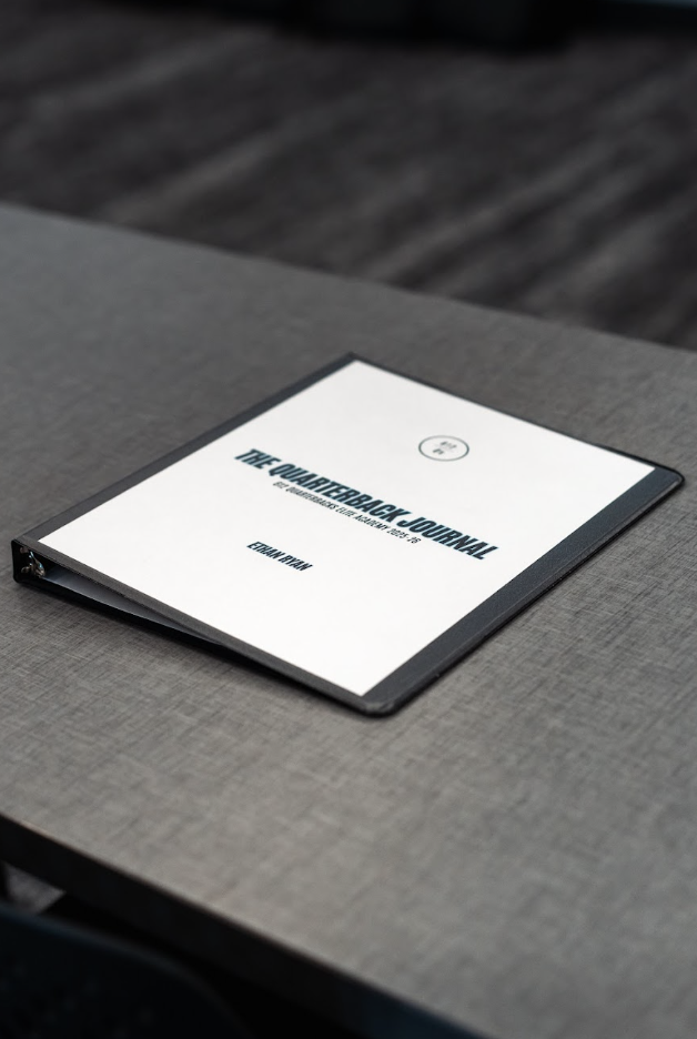 An electronic tablet displaying the cover page of The Quarterback Journal placed on a gray fabric-covered surface.