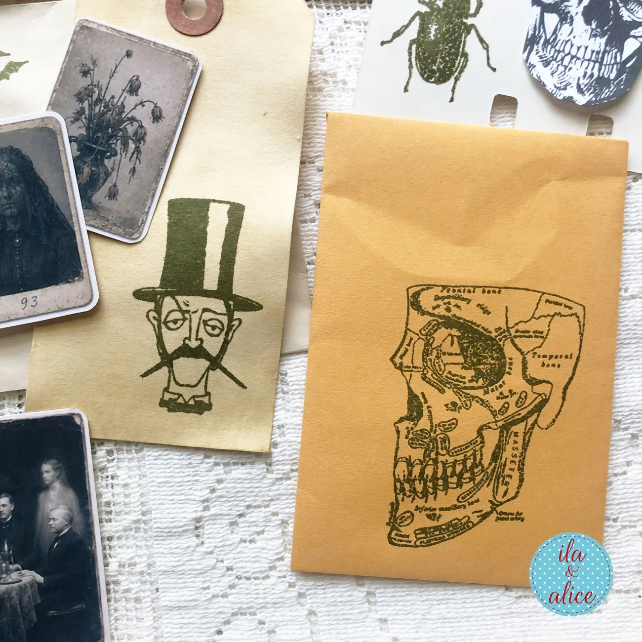 Haunted ephemera featuring a stamped anatomical skull on an ochre envelope, a Victorian-style gentleman in a top hat, aged tags and small eerie portrait cards.