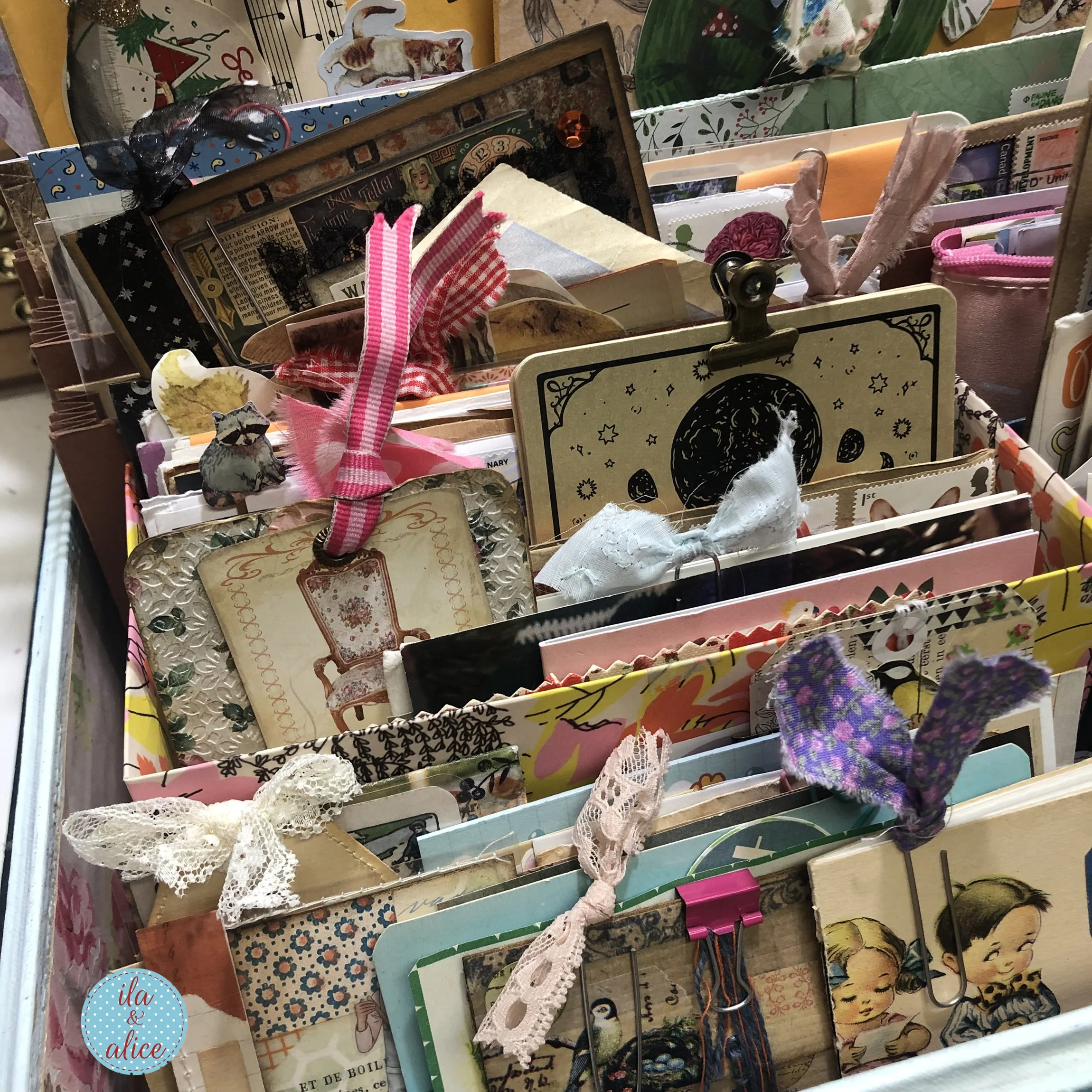 Organized happy mail inside a vintage suitcase with handmade tags, postcards, ribbon, lace, paper clips, illustrated cards, and colourful paper ephemera.