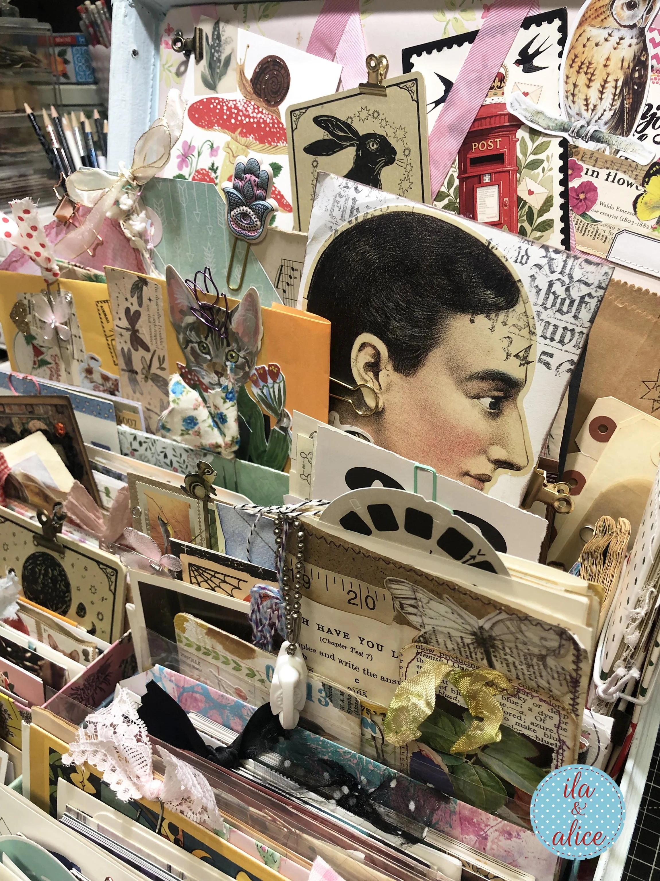 Close-up of a vintage suitcase archive filled with happy mail, handmade paper treasures, tags, envelopes, clips, ribbon, owl art, cat art, and collage pieces.