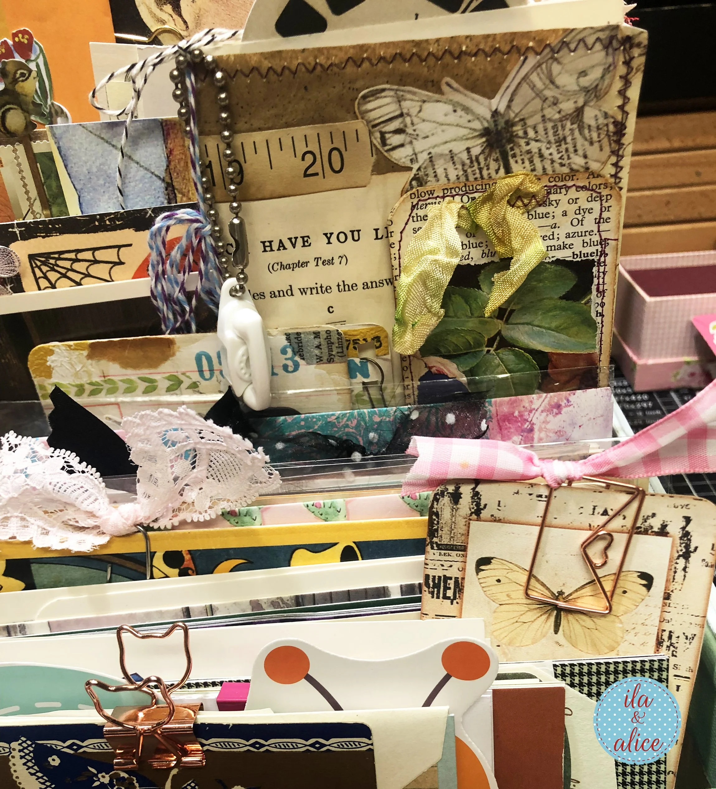 Close-up of a happy mail suitcase filled with butterfly tags, paper clips, ribbon, lace, handmade cards, envelopes, and layered paper keepsakes.