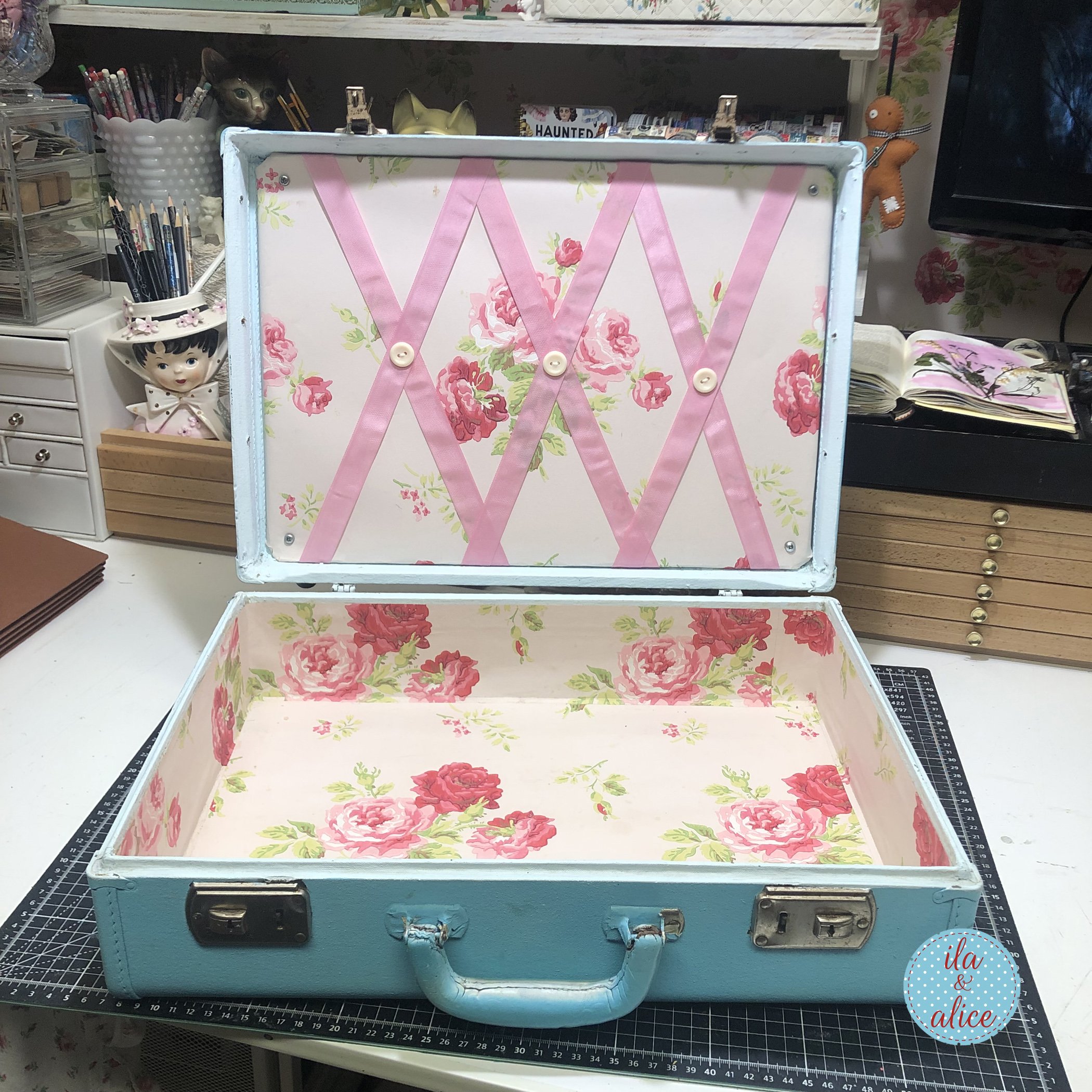 Empty vintage blue suitcase lined with floral paper and pink ribbon, ready to be turned into a happy mail archive.