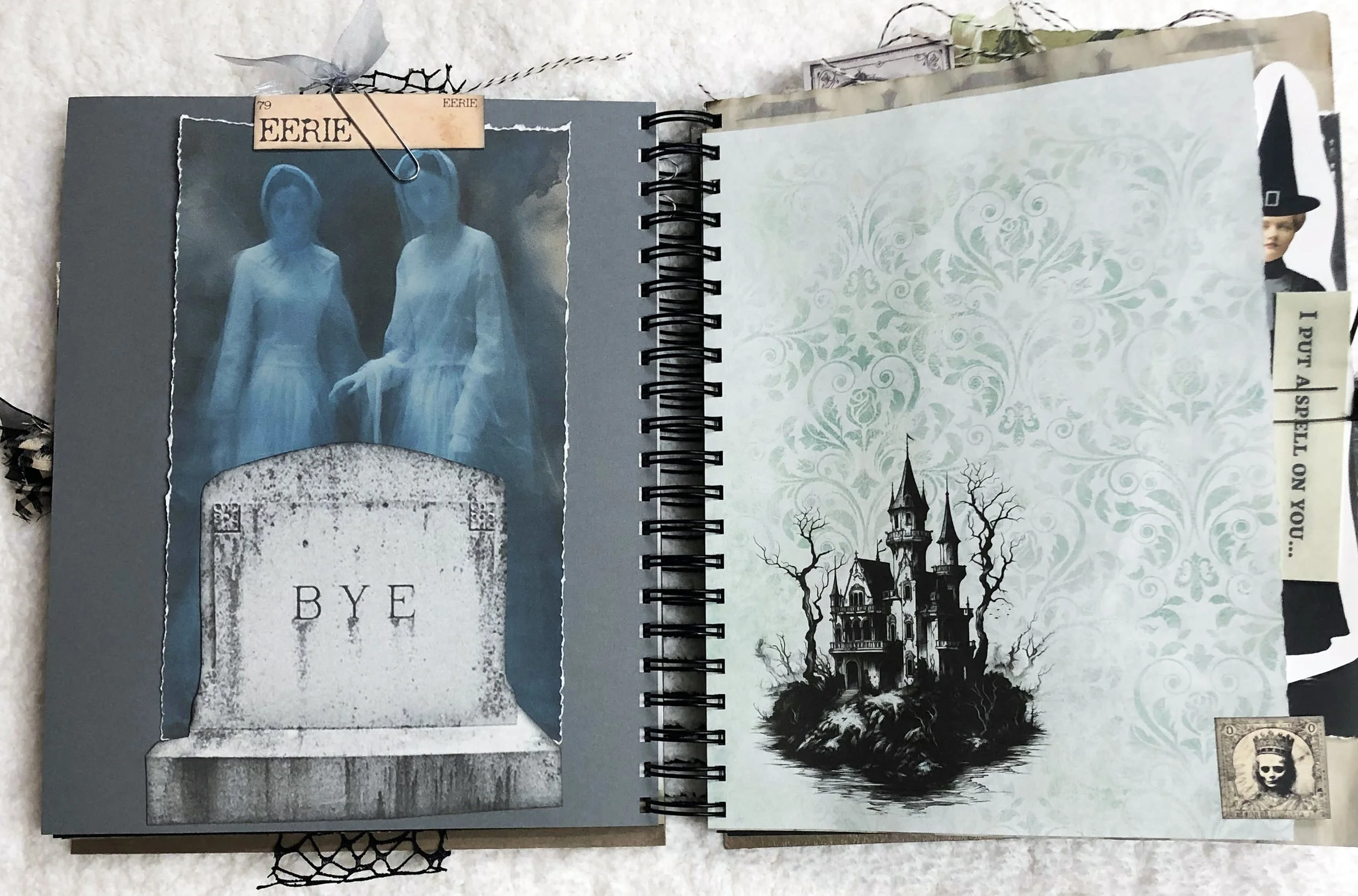 Ghostly figures rise behind a tombstone beside a pale haunted house page in the handmade witch journal.