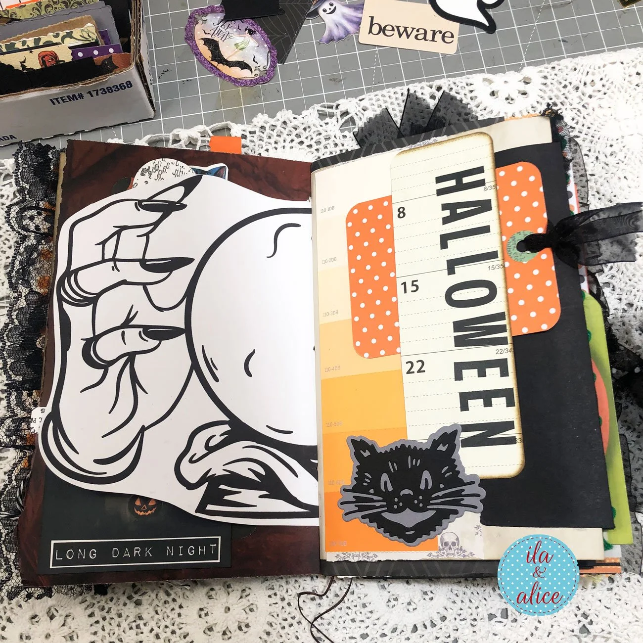 Interactive Halloween junk journal spread with a large illustrated hand, orange polka-dot pocket, black cat and oversized Halloween tag