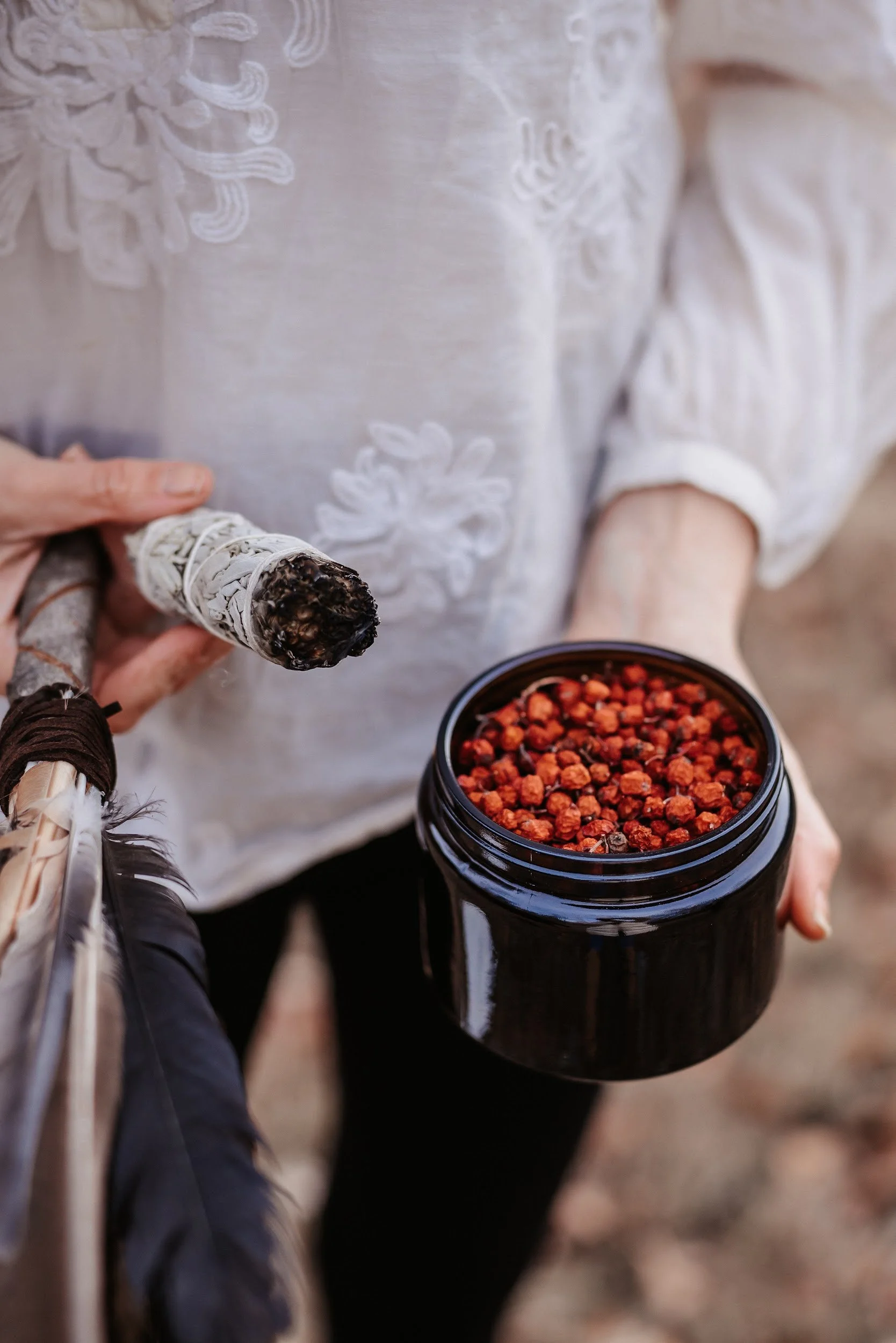 Person hält eine Räucherkerze in der Hand, neben einem offenen schwarzen Behälter mit roten Räucherkerzen.