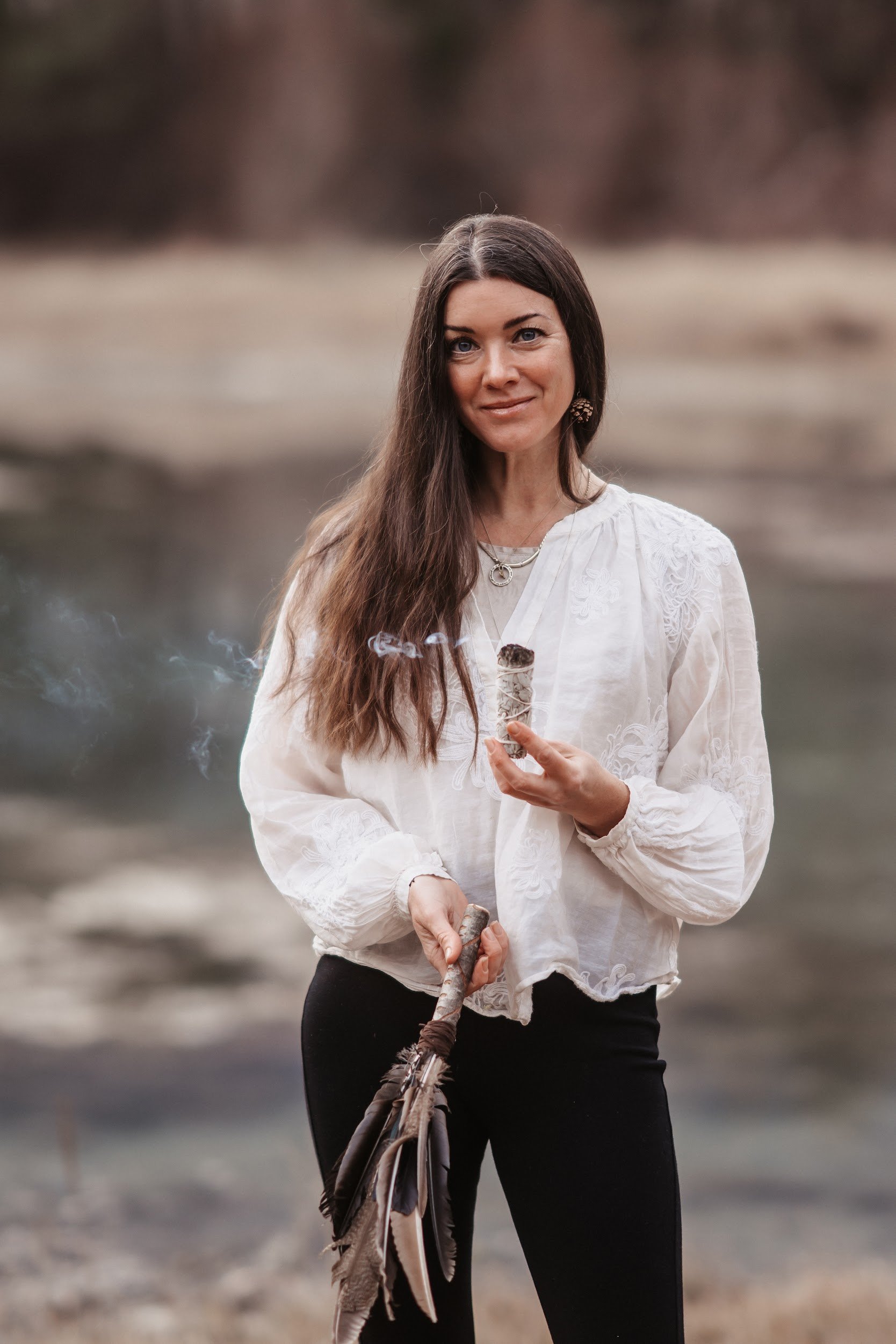 Carolin Hacker trägt in der linken hand ein bündel Salbe zum Räuhern und in der rechten hand einen Fächer aus Federn.