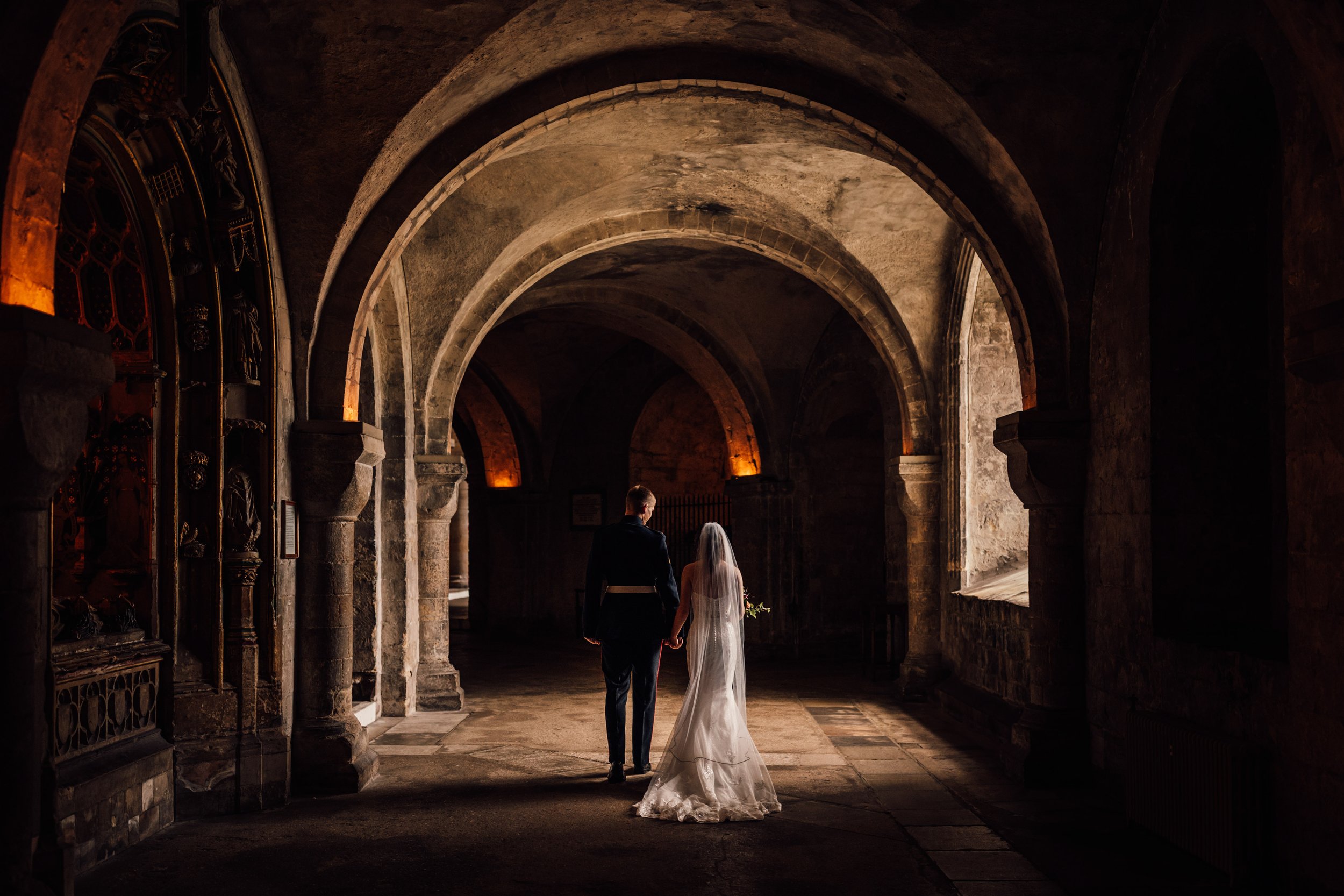 bride and groom walking away from camera in an old ancient crypt