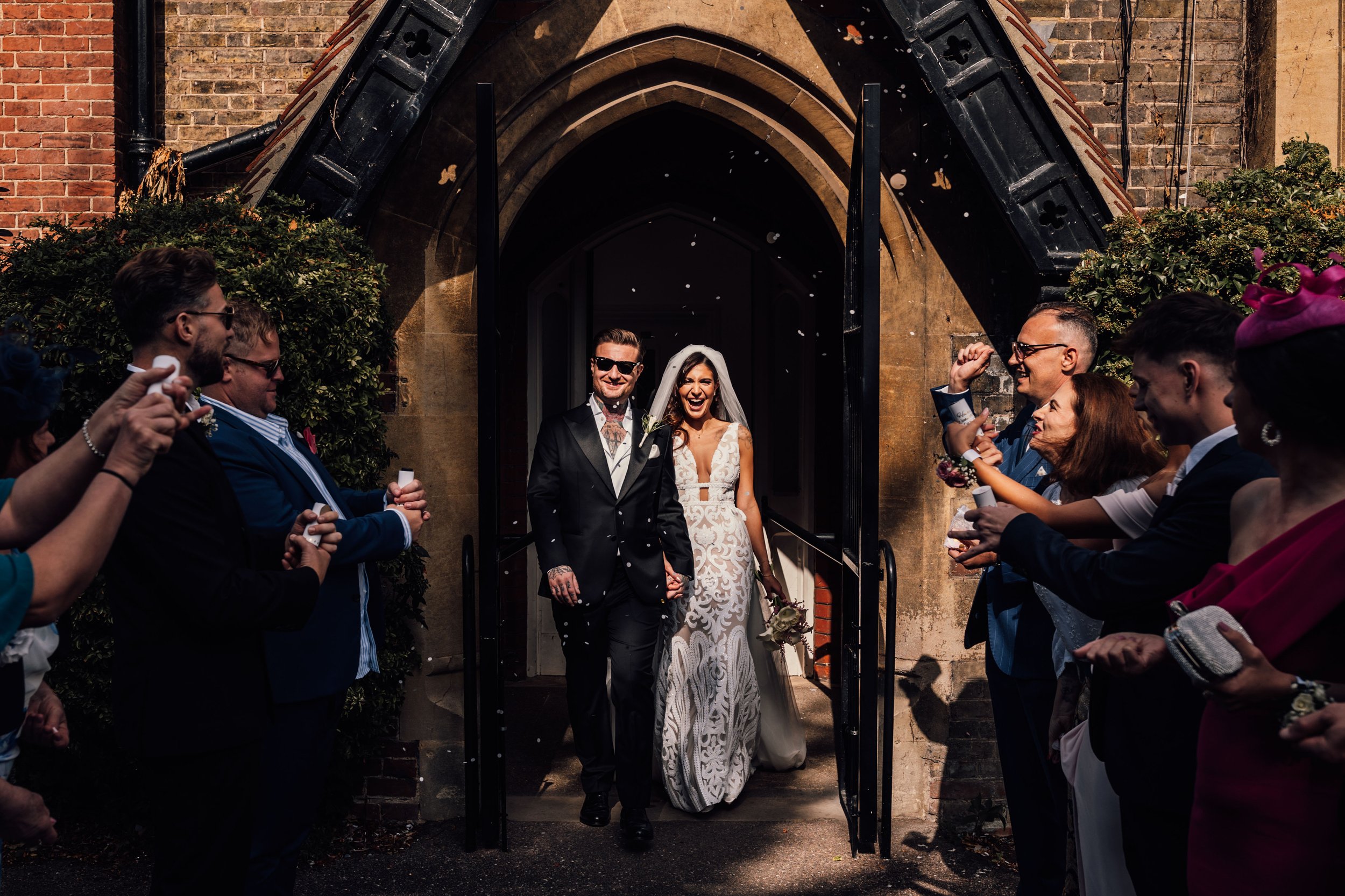 guests throwing confetti over bride & groom as they leave ceremony