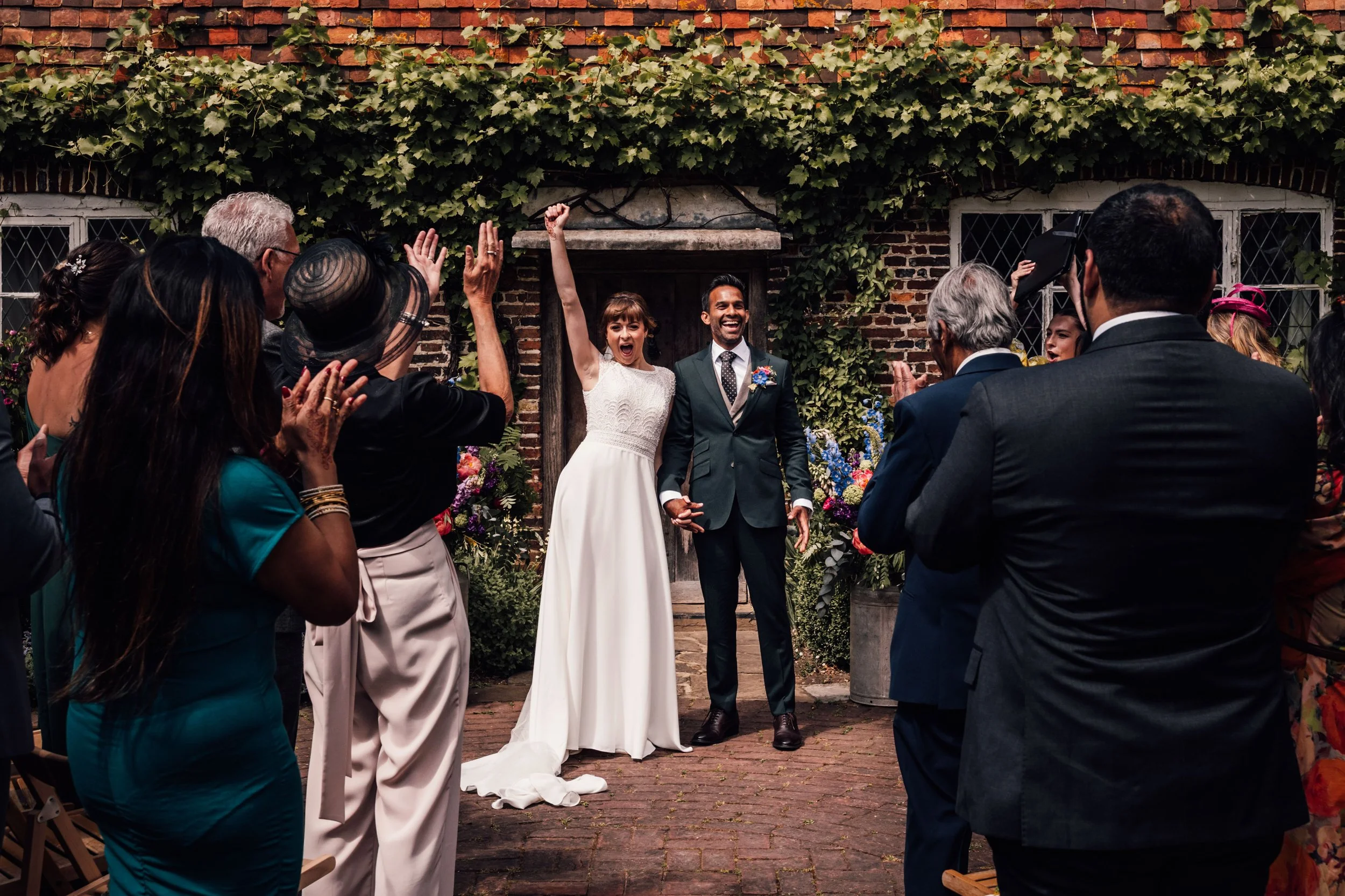 bride and groom cheering during their wedding ceremony with guests clapping